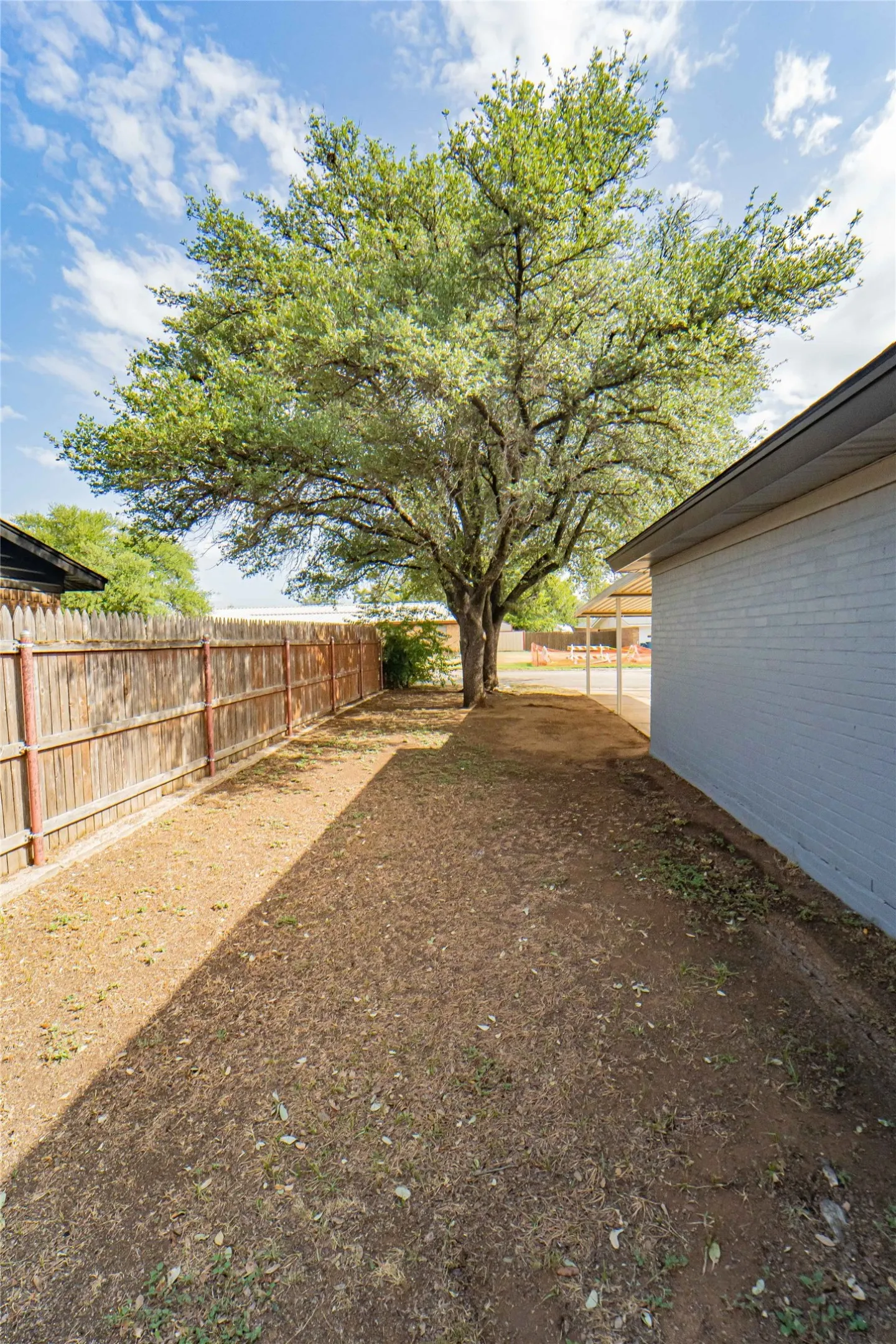 Plenty of evening shade-Expansive side yard featuring a mature tree, wood privacy fencing, and a brick exterior wall