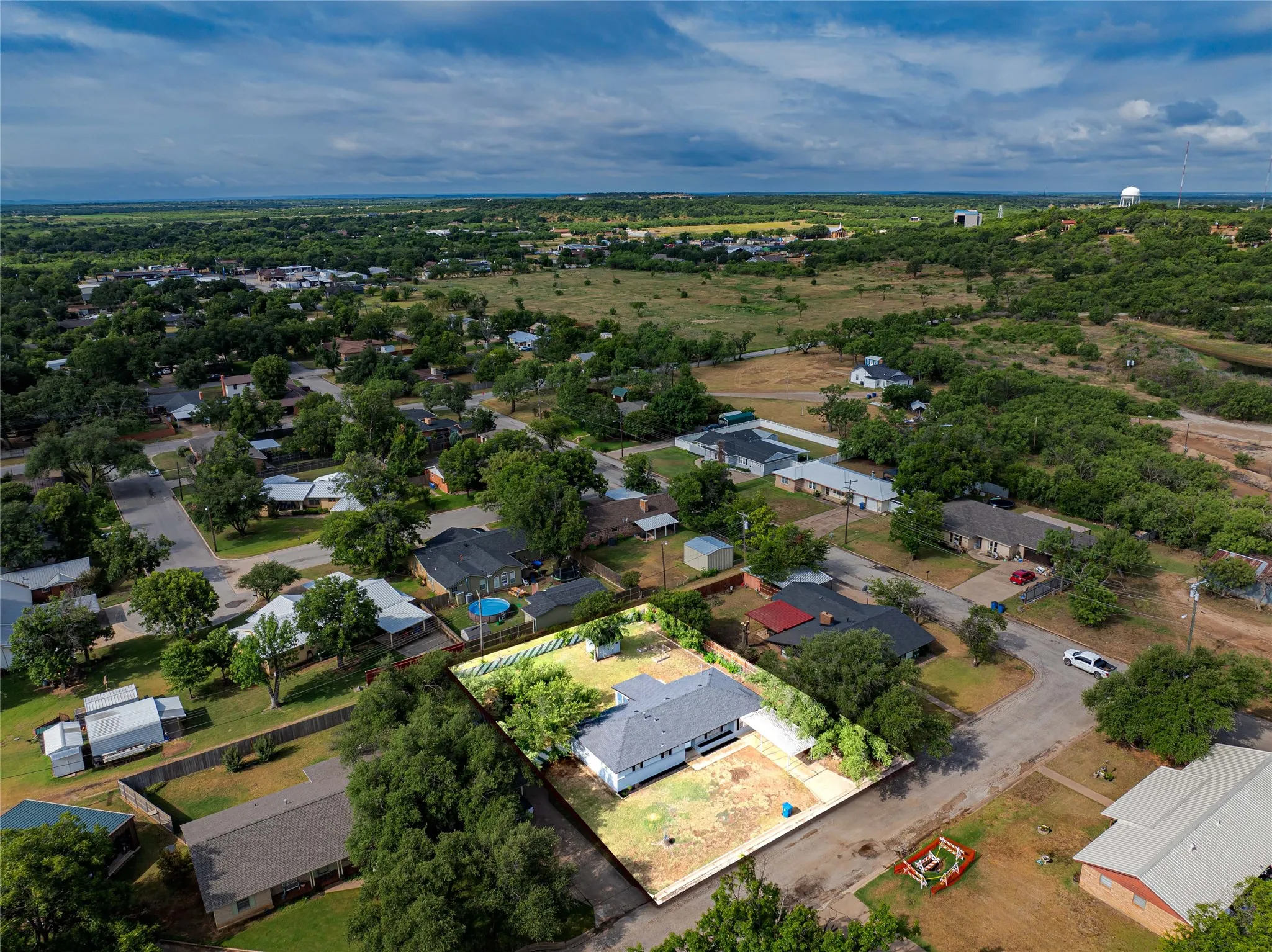 Located in a quiet, established neighborhood-Aerial perspective highlighting the property's expansive lot, mature trees, and surrounding neighborhood with paved roads