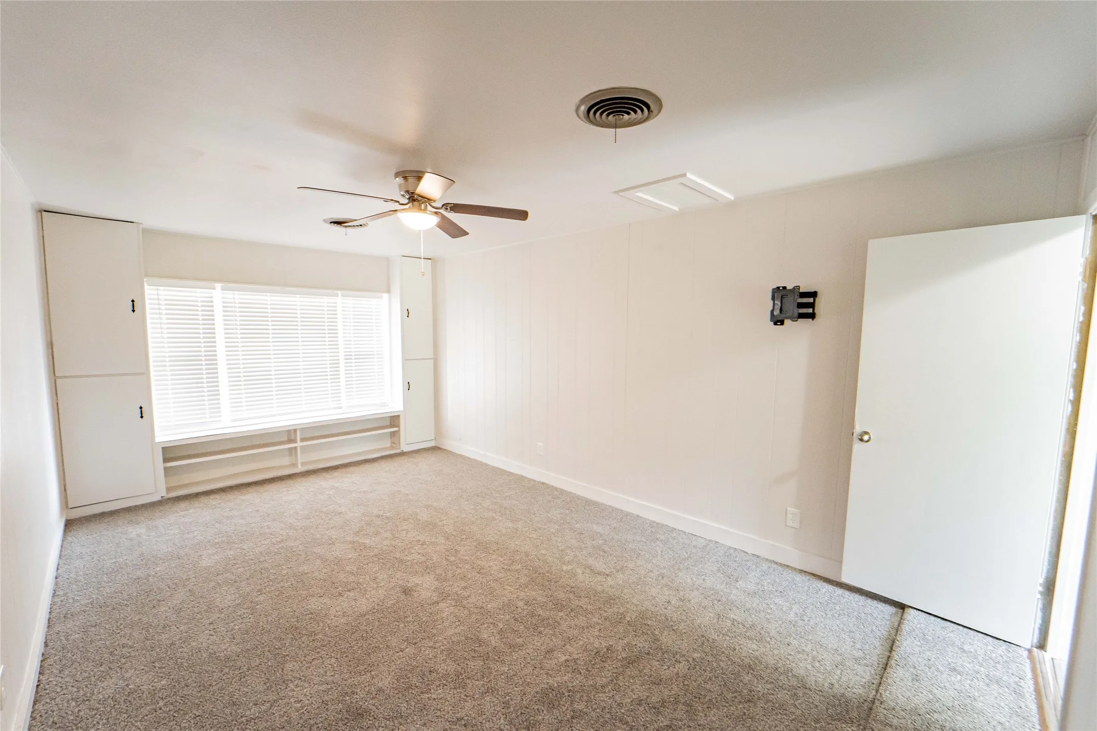 4th Bedroom or optional second living area- Spacious room featuring neutral carpet, a ceiling fan with light fixture, and a built-ins with integrated shelving