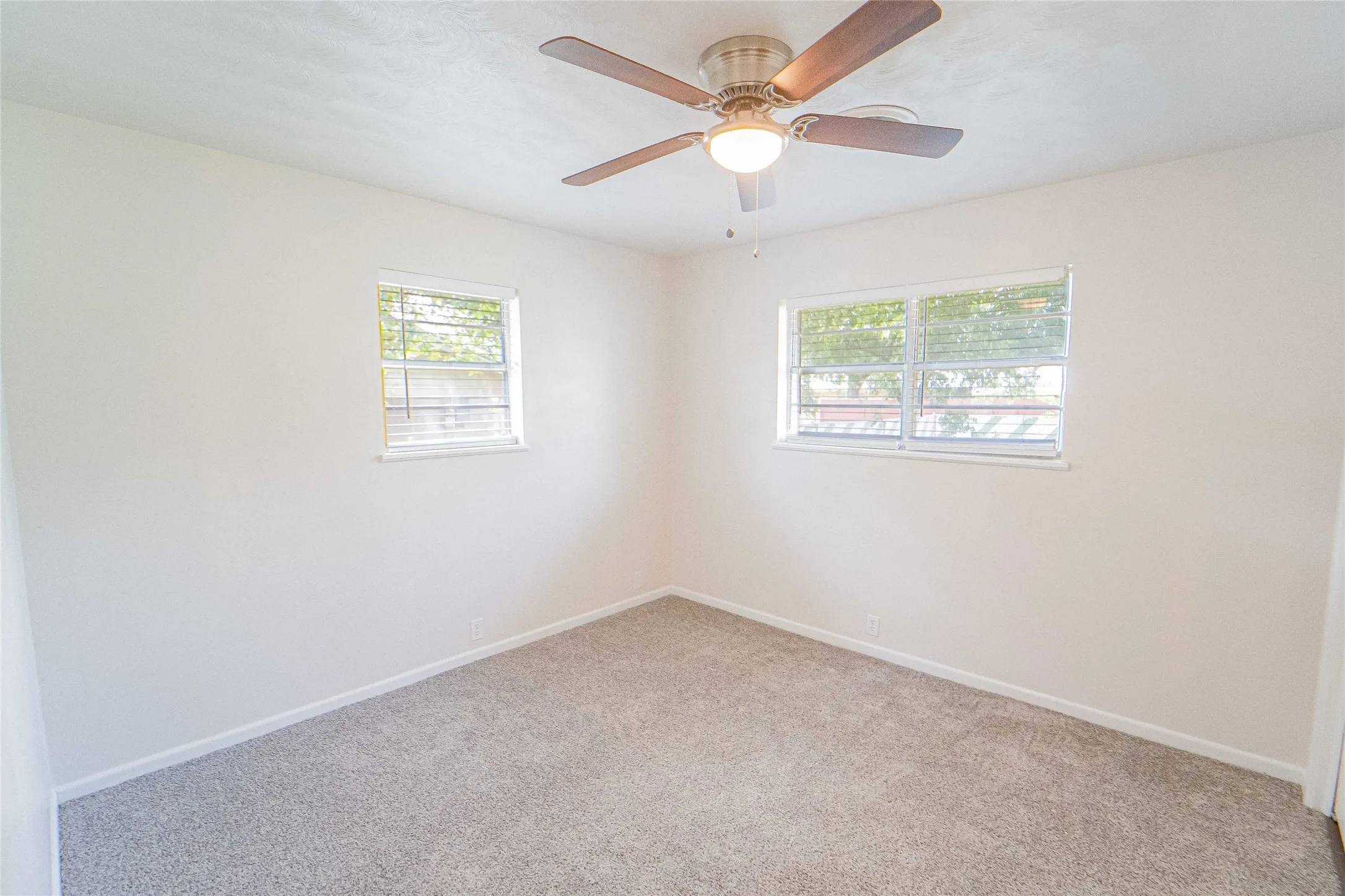Bedroom 2 of 4/Neutral wall color featuring new carpet, blinds, and a ceiling fan with integrated lighting.