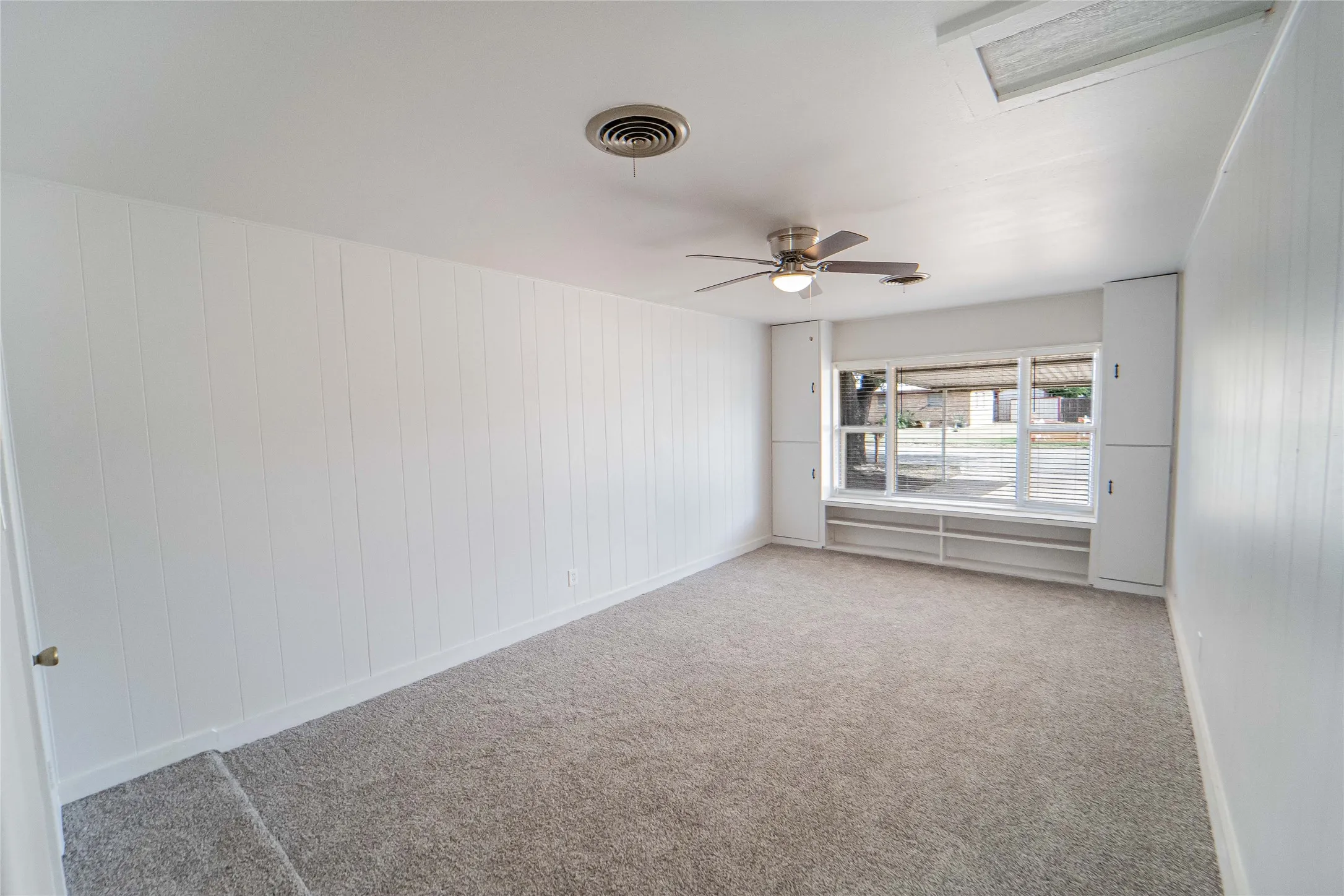 Bedroom 4 of 4/could be used as a flex room/second living area- Carpeted room featuring a ceiling fan with integrated lighting, a large window with white blinds, and built-in cabinetry flanking the window