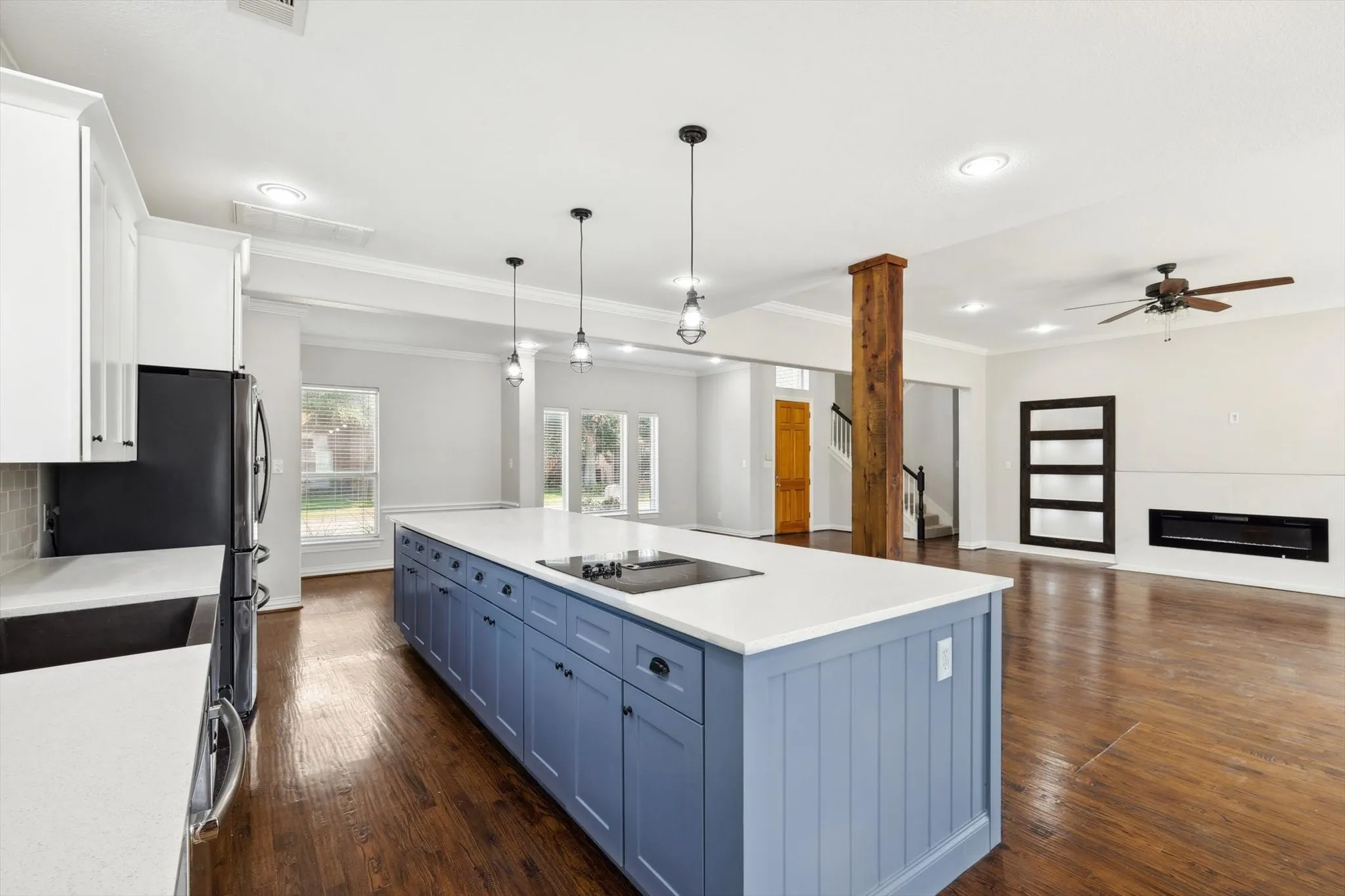 Kitchen featuring dark hardwood / wood-style floors, white cabinets, hanging light fixtures, crown molding, and a kitchen island
