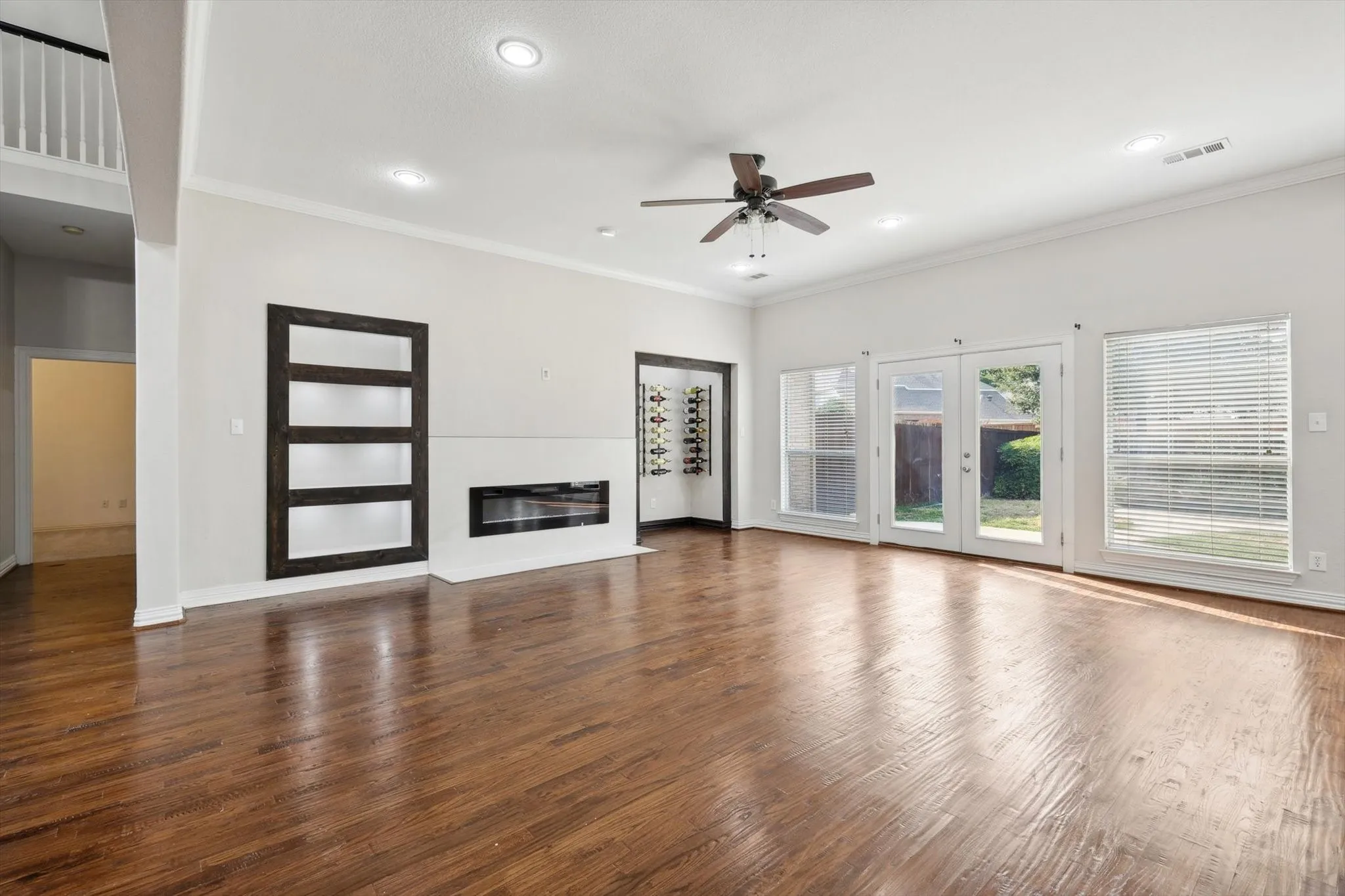 Unfurnished living room featuring ornamental molding, dark wood-type flooring, and ceiling fan
