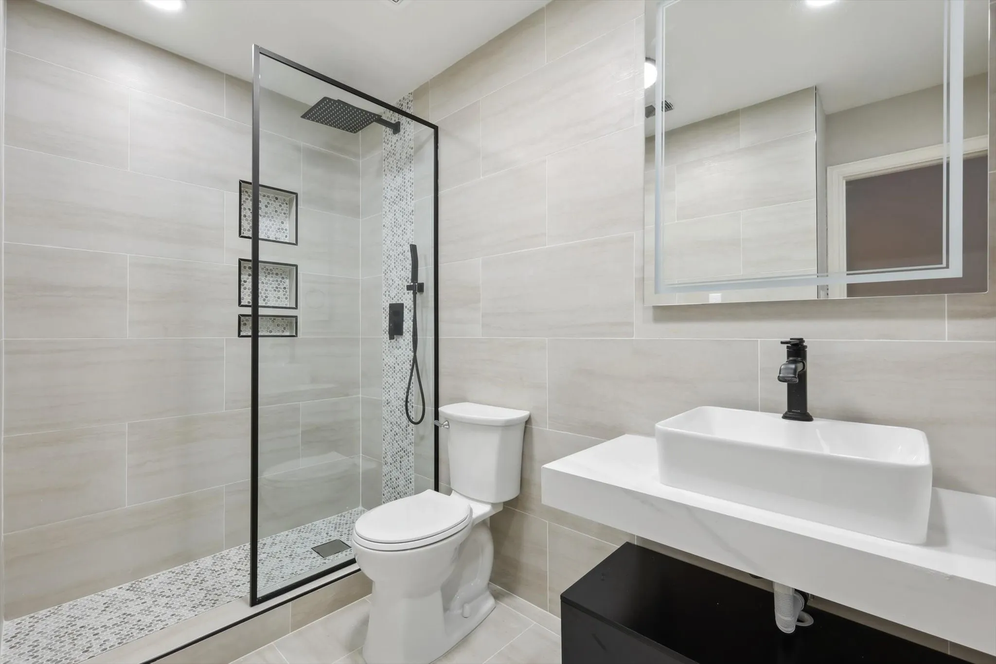 Bathroom with sink, tile walls, walk in shower, and toilet