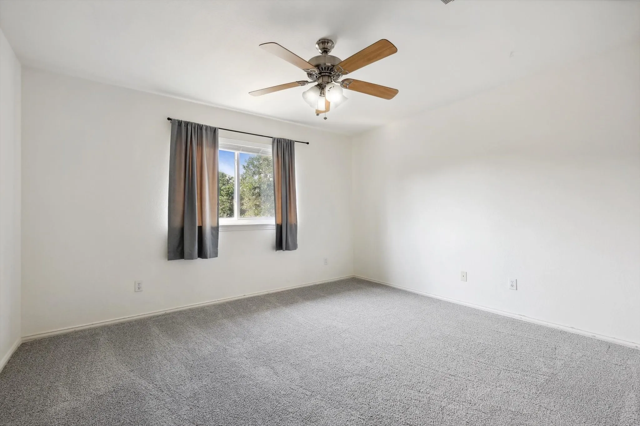 Carpeted spare room featuring ceiling fan