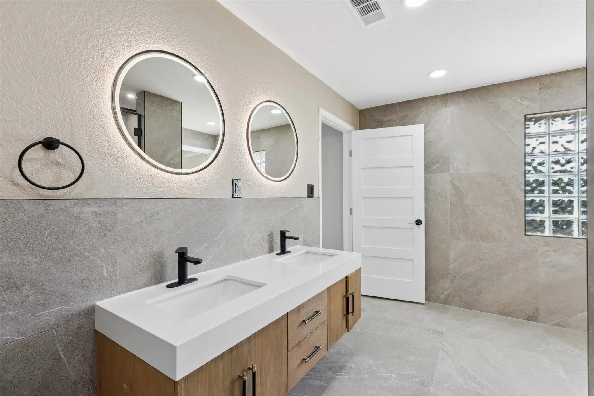 Bathroom with dual bowl vanity and tile walls