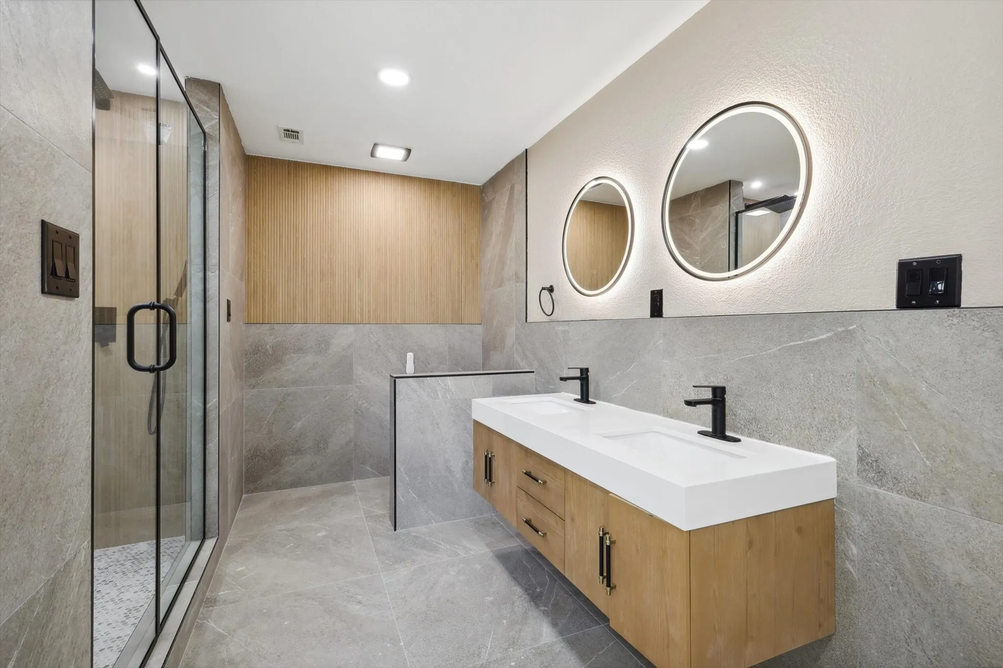 Bathroom featuring dual vanity, tile walls, and walk in shower