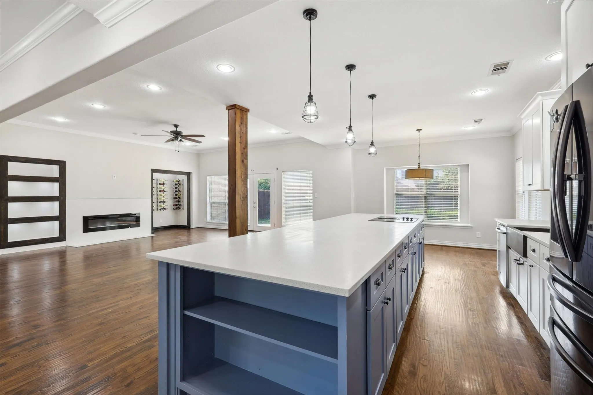 Kitchen featuring dark hardwood / wood-style flooring, a center island, ceiling fan, white cabinets, and decorative light fixtures
