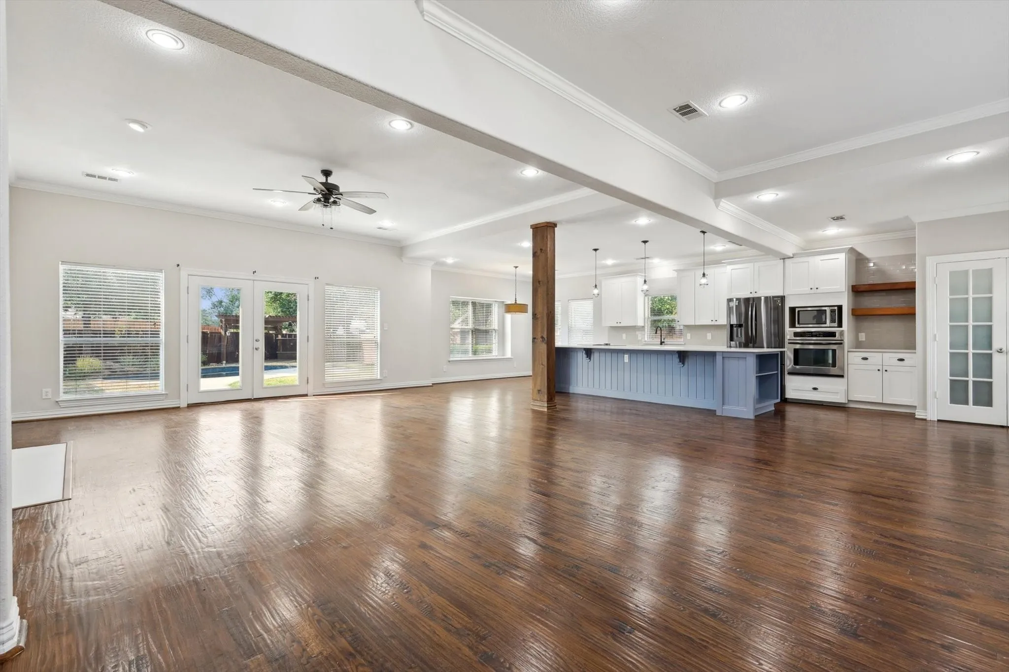 Unfurnished living room with hardwood / wood-style floors, crown molding, and a healthy amount of sunlight.