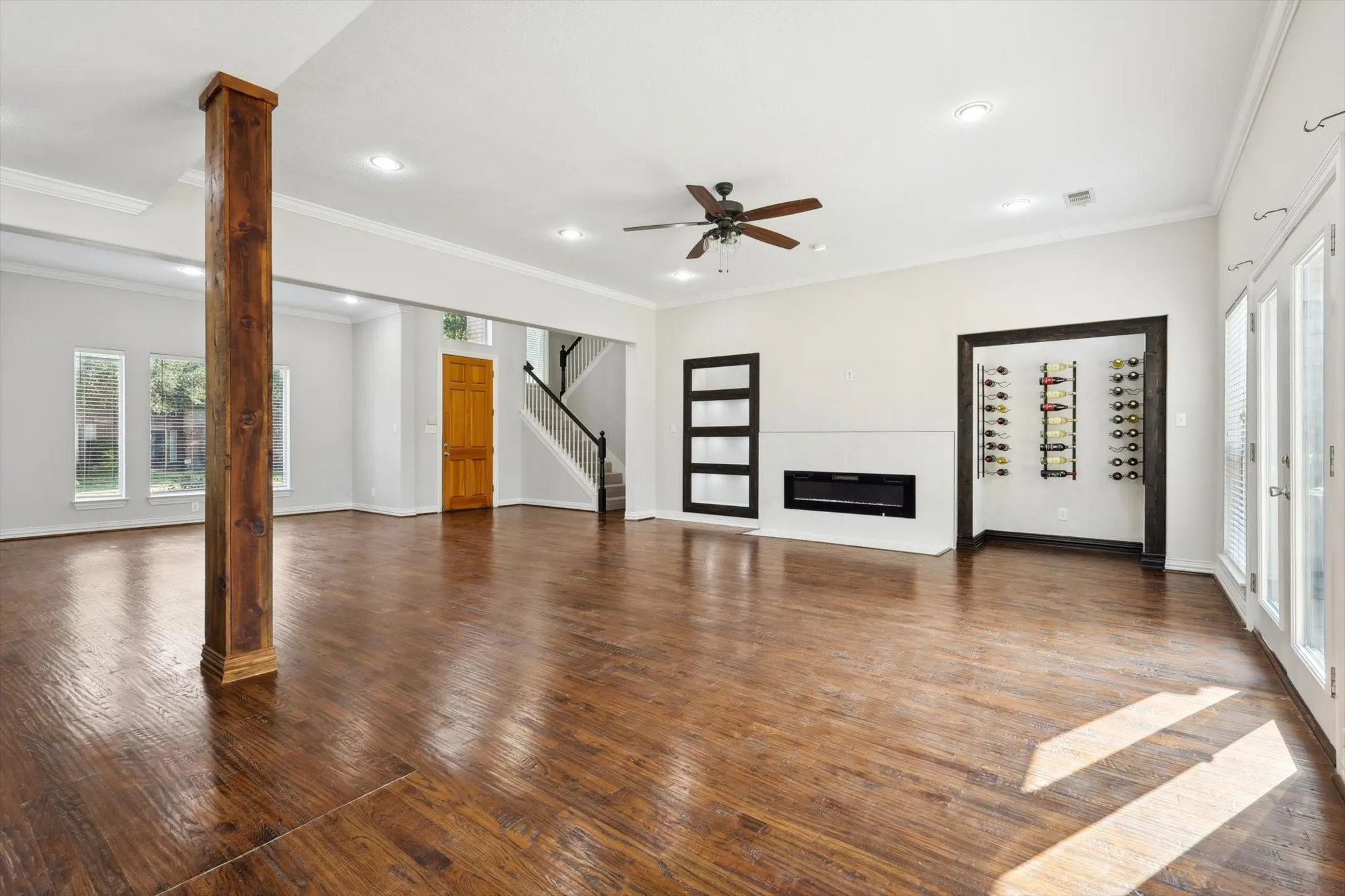 Unfurnished living room with ceiling fan, crown molding, dark hardwood / wood-style flooring, and decorative columns