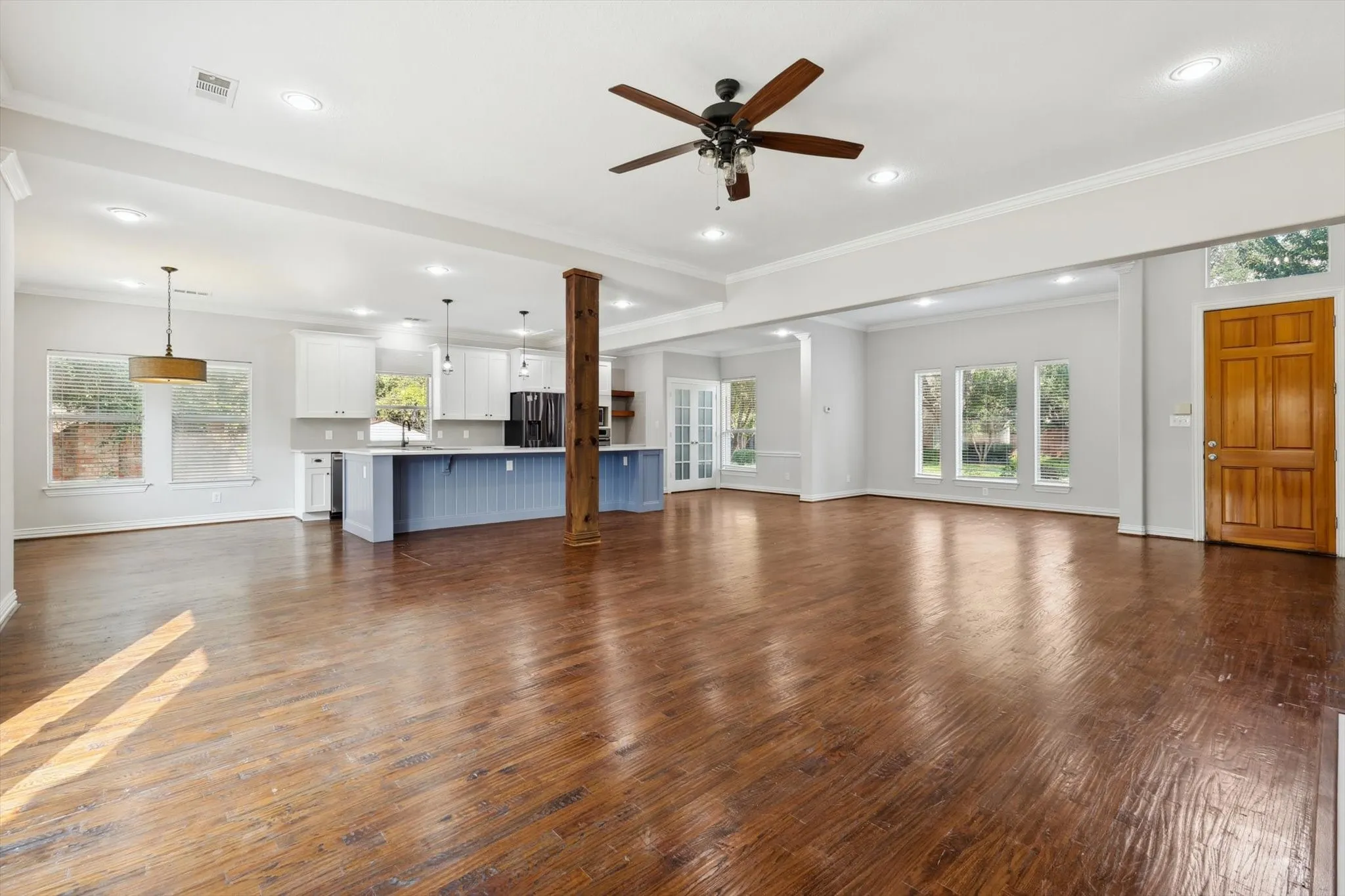 Unfurnished living room featuring ceiling fan, sink, dark hardwood / wood-style flooring, and ornamental molding