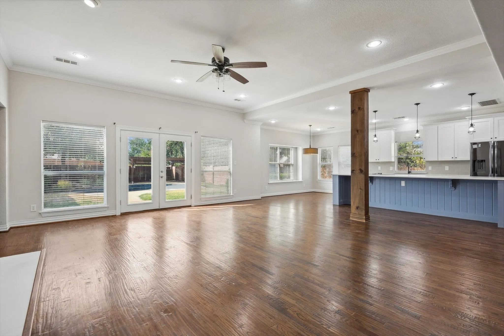 Unfurnished living room with ceiling fan, french doors, crown molding, and wood-type flooring