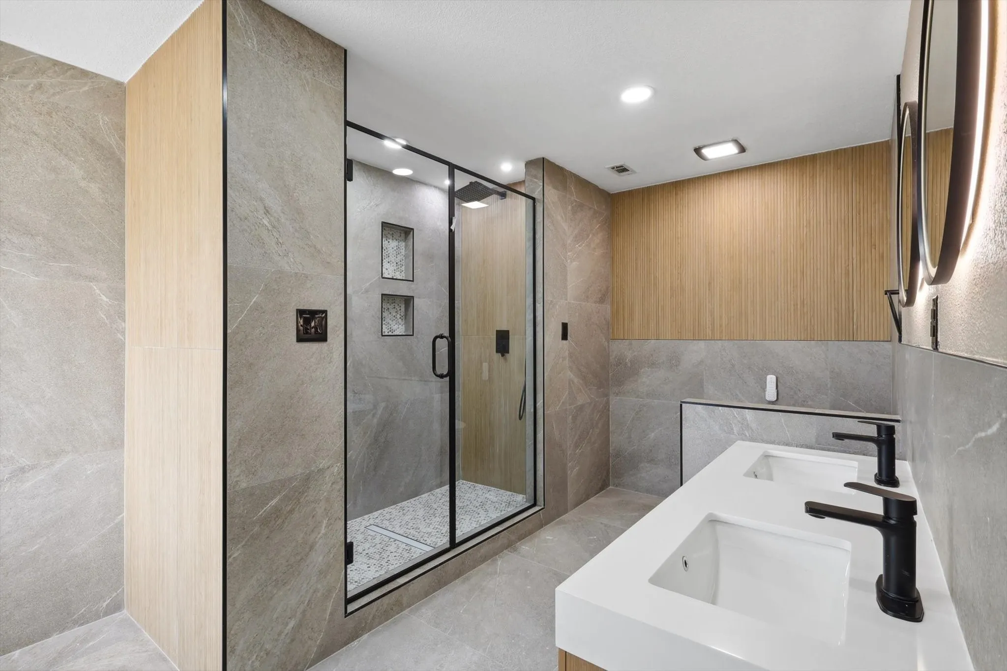 Bathroom featuring tile walls, an enclosed shower, tile patterned flooring, and dual sinks