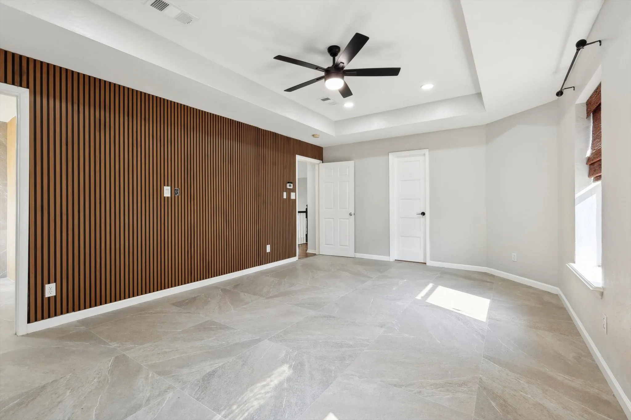 Unfurnished room with ceiling fan, light tile patterned floors, and a tray ceiling