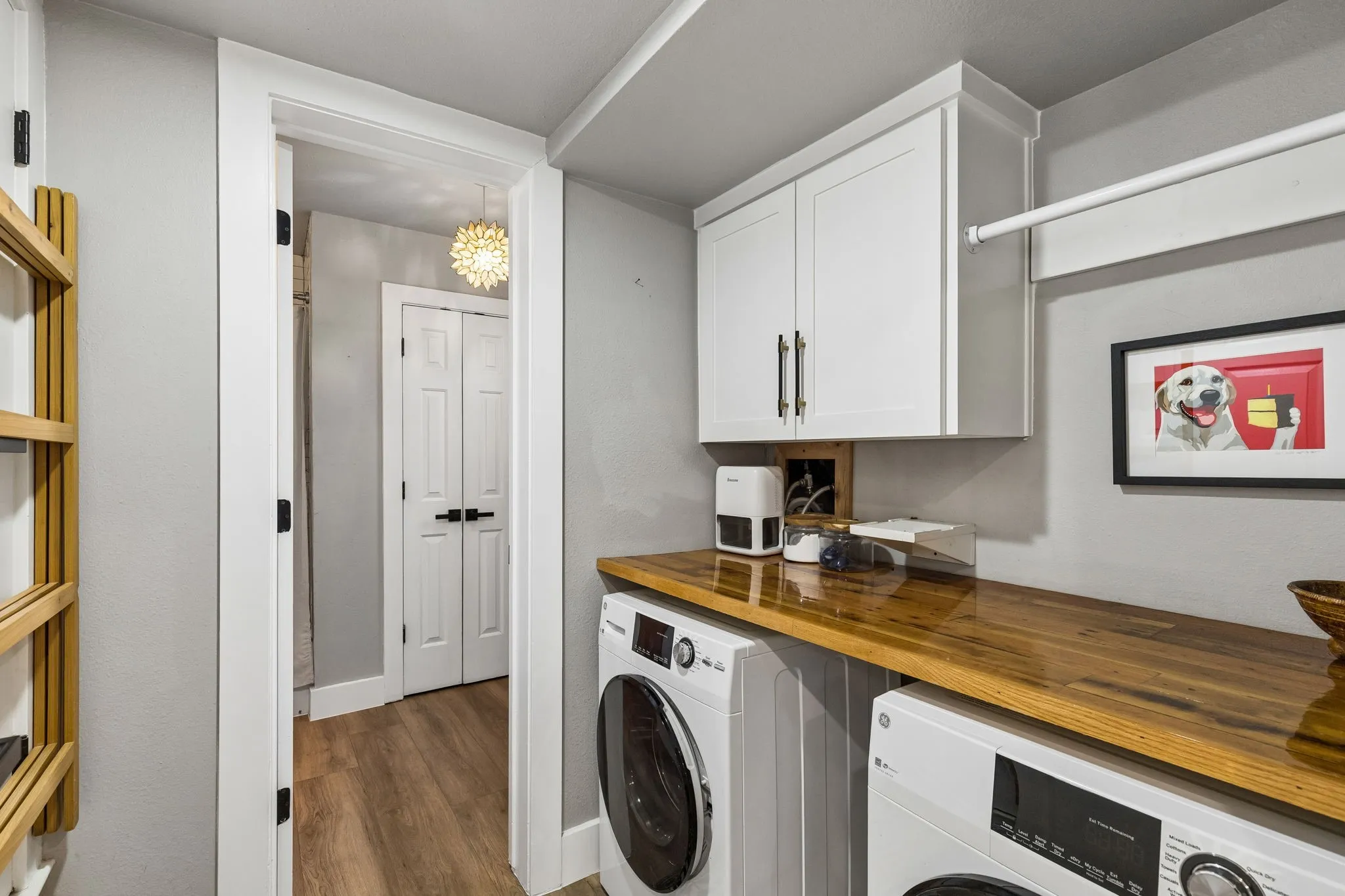 Laundry area featuring a wood-finish countertop, white upper cabinetry, and a clothes hanging rod