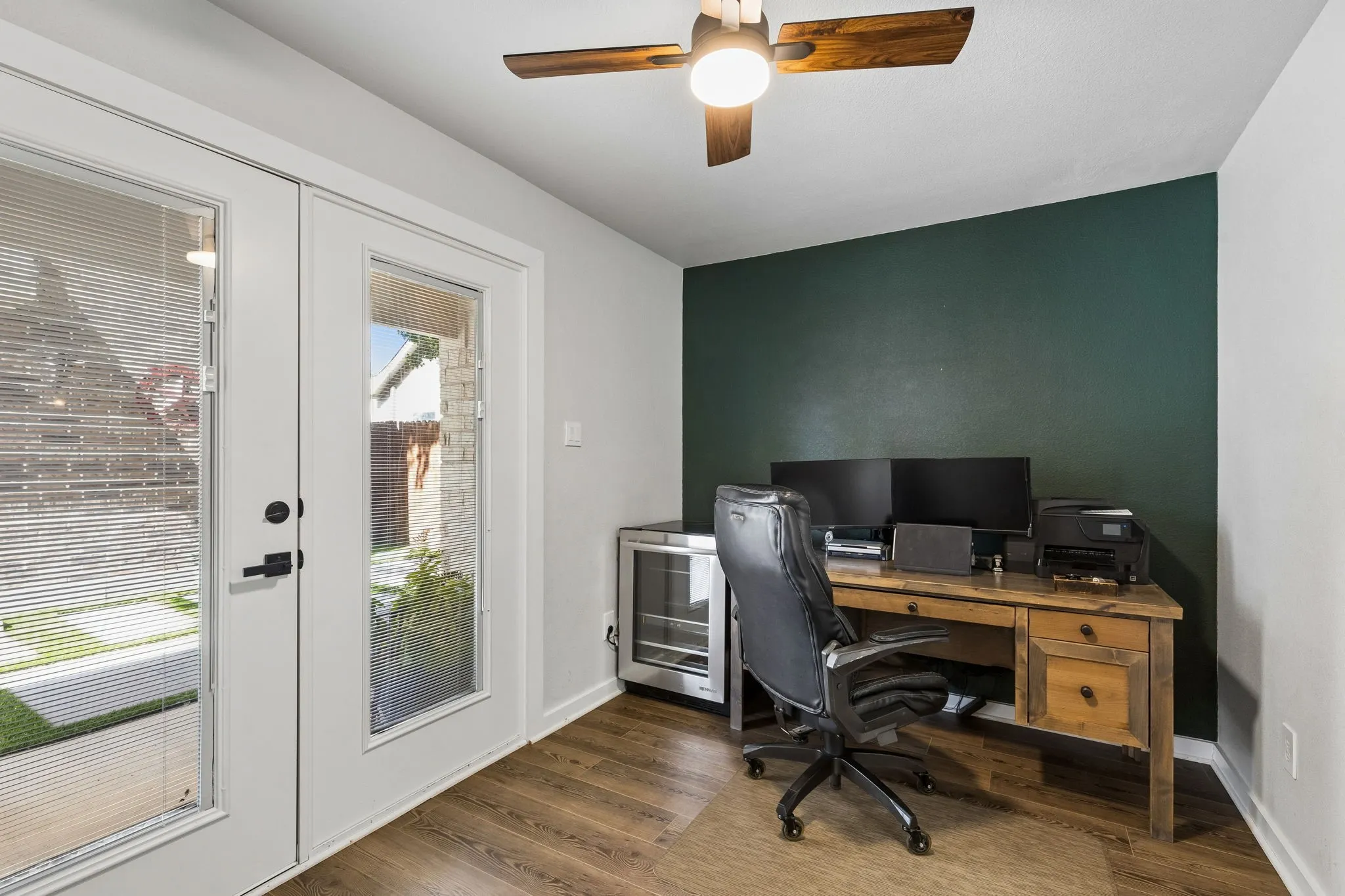 Room featuring wood-finish flooring, a ceiling fan with integrated lighting, and a dark accent wall
