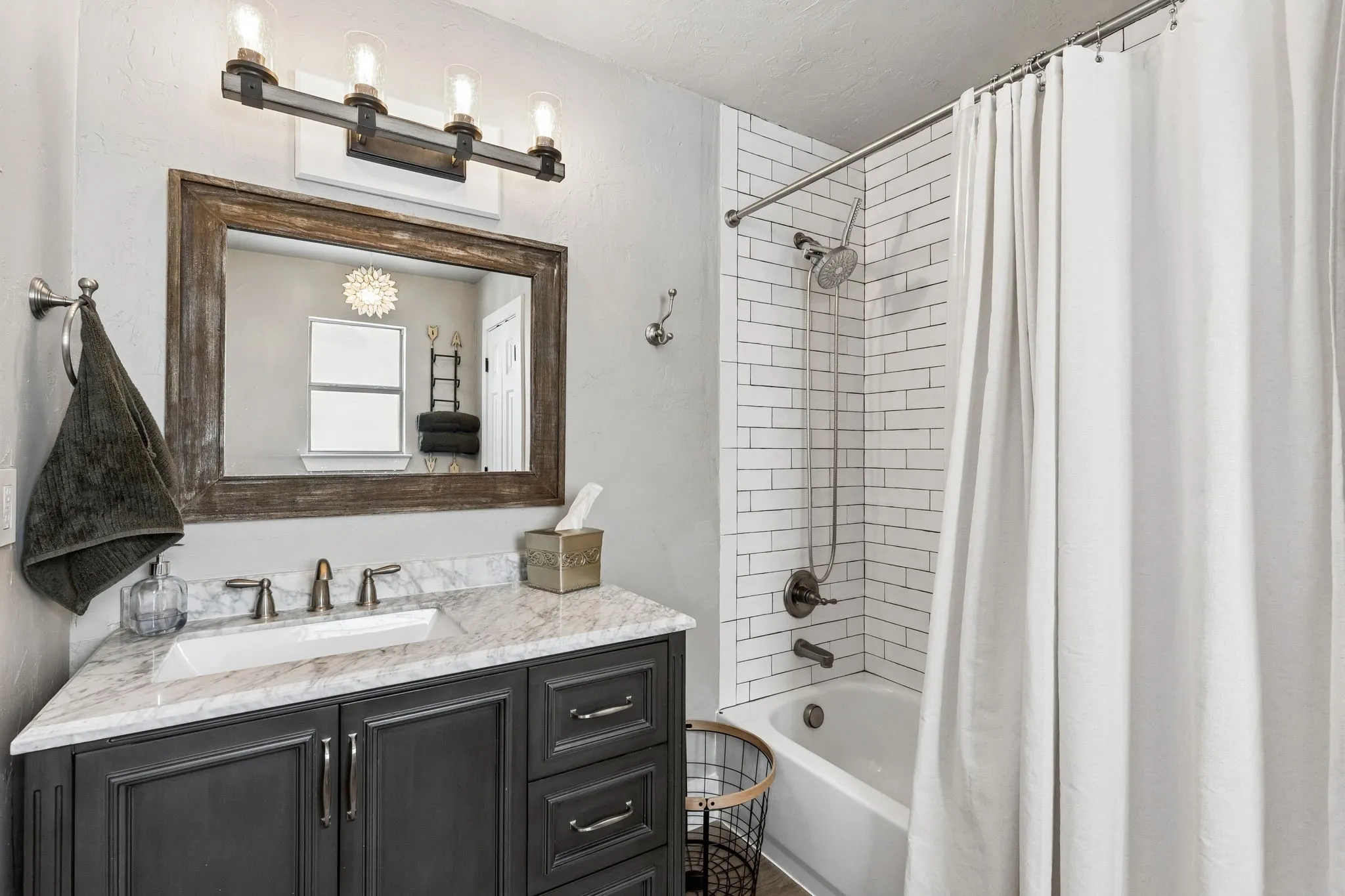 Bathroom featuring a dark wood vanity with a light-toned countertop, a rectangular undermount sink, and a framed mirror