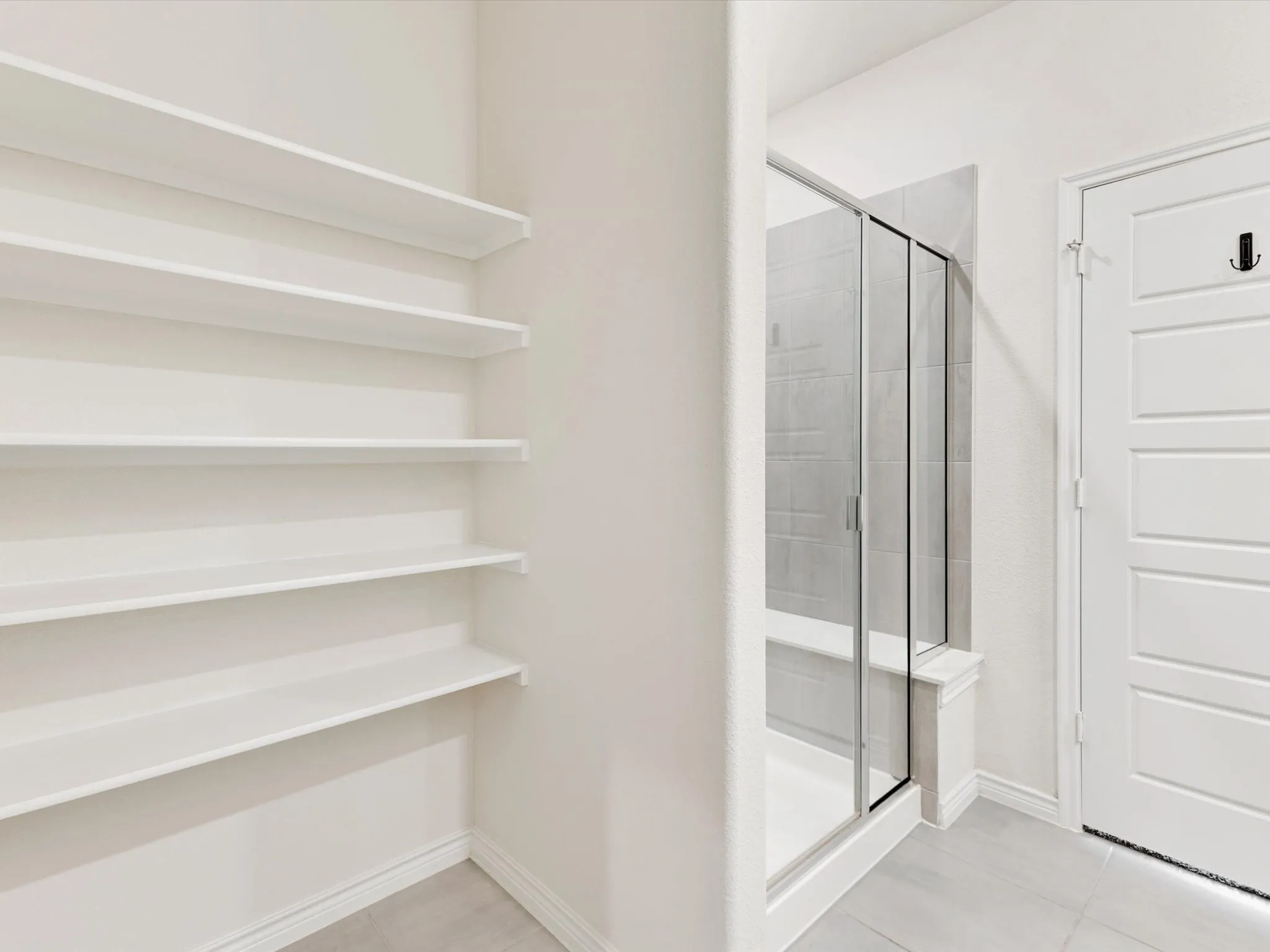 Primary bathroom featuring built-in shelving and walk-in-shower