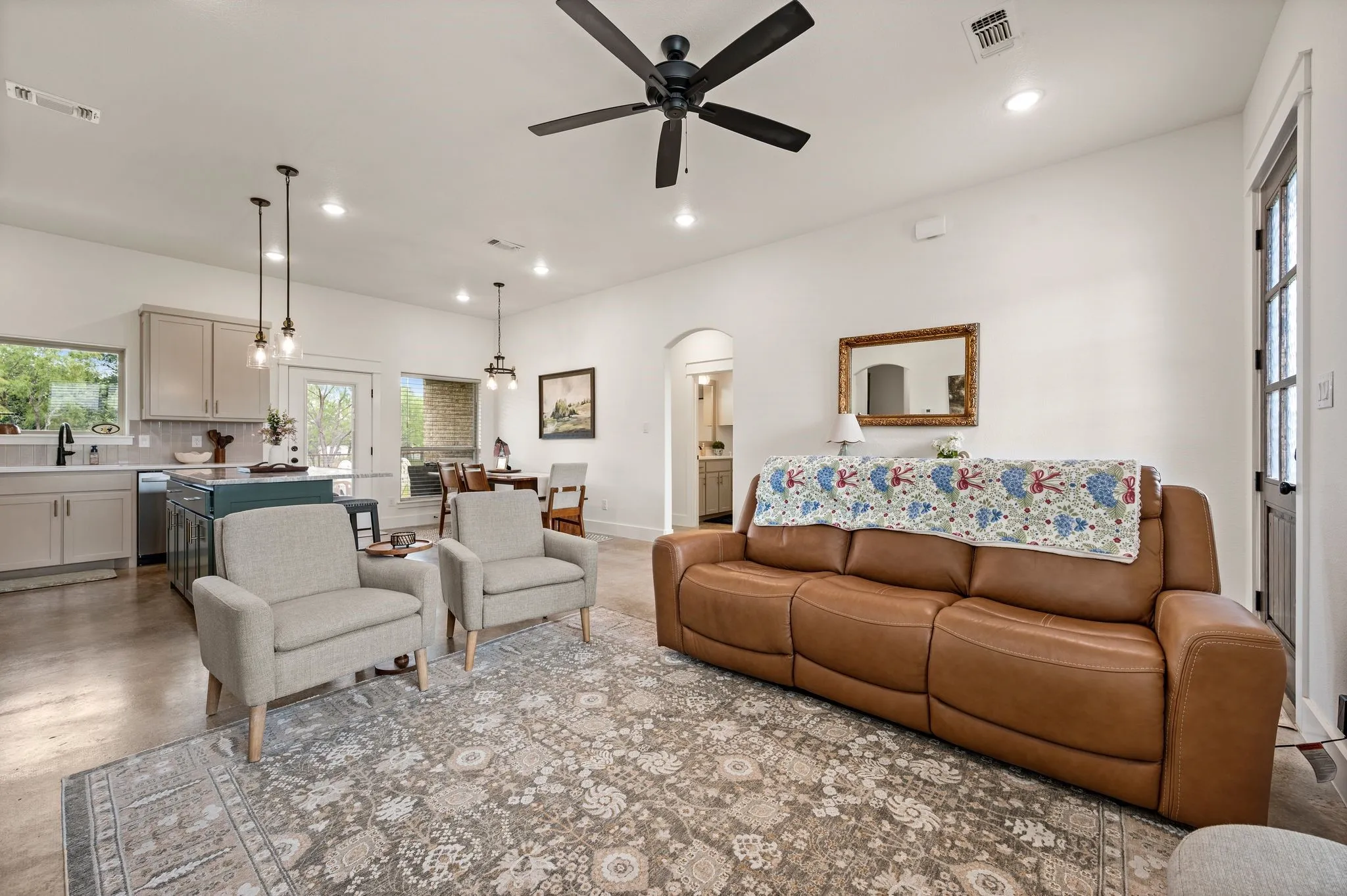 Open-concept living area with concrete flooring, recessed lighting, and a ceiling fan