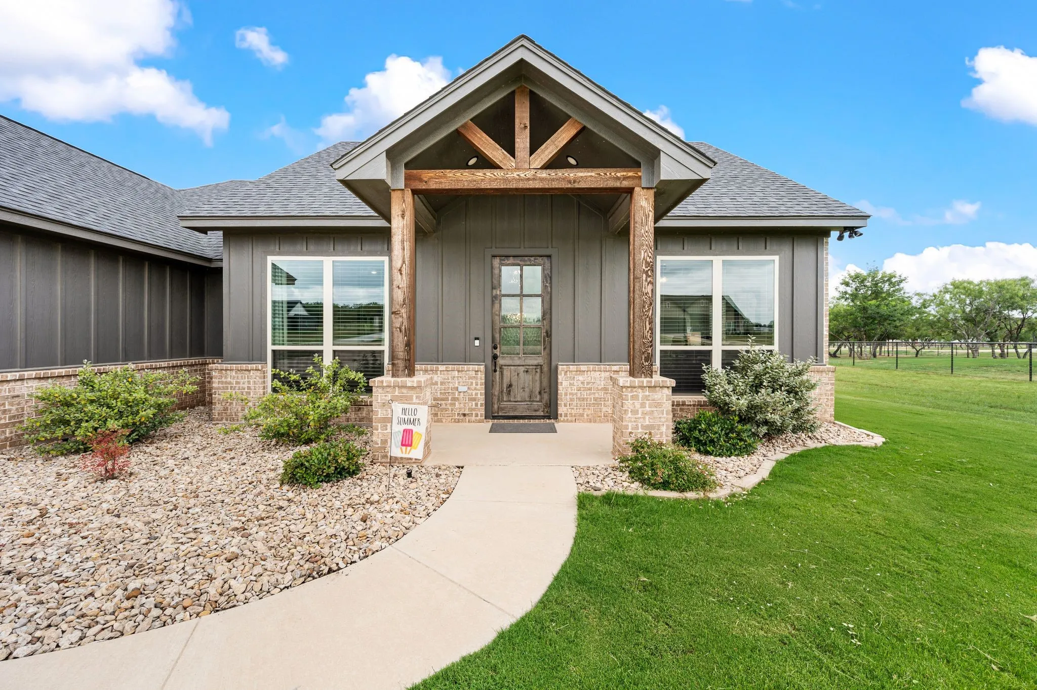 Inviting front exterior featuring a covered entry, vertical siding, brick accents, and a wood-finish front door