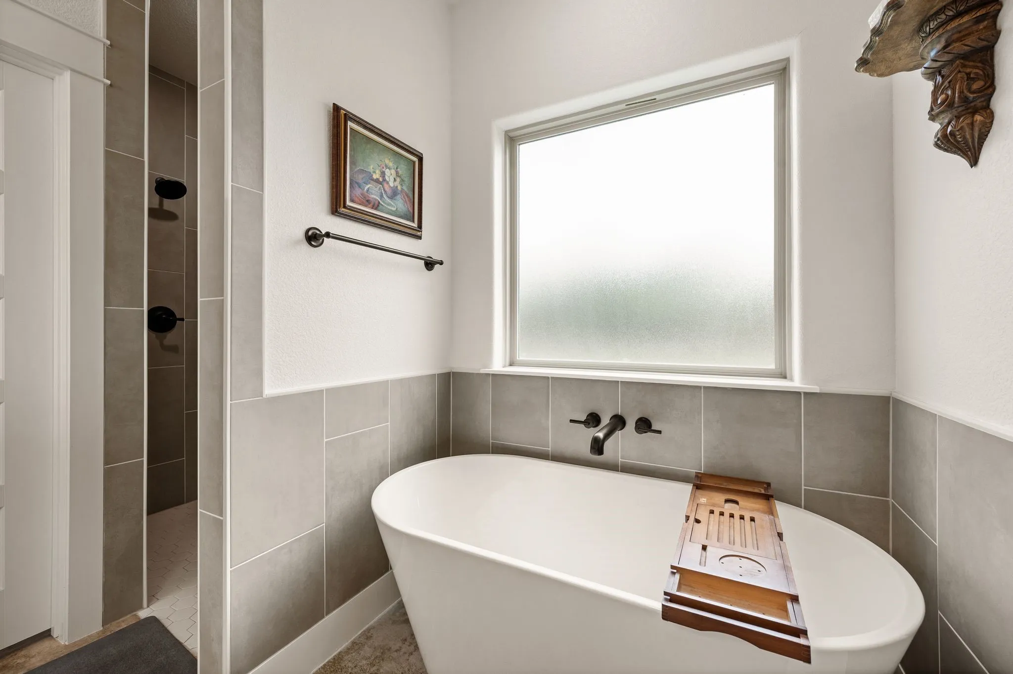 Freestanding white soaking tub with wall-mounted matte black faucet