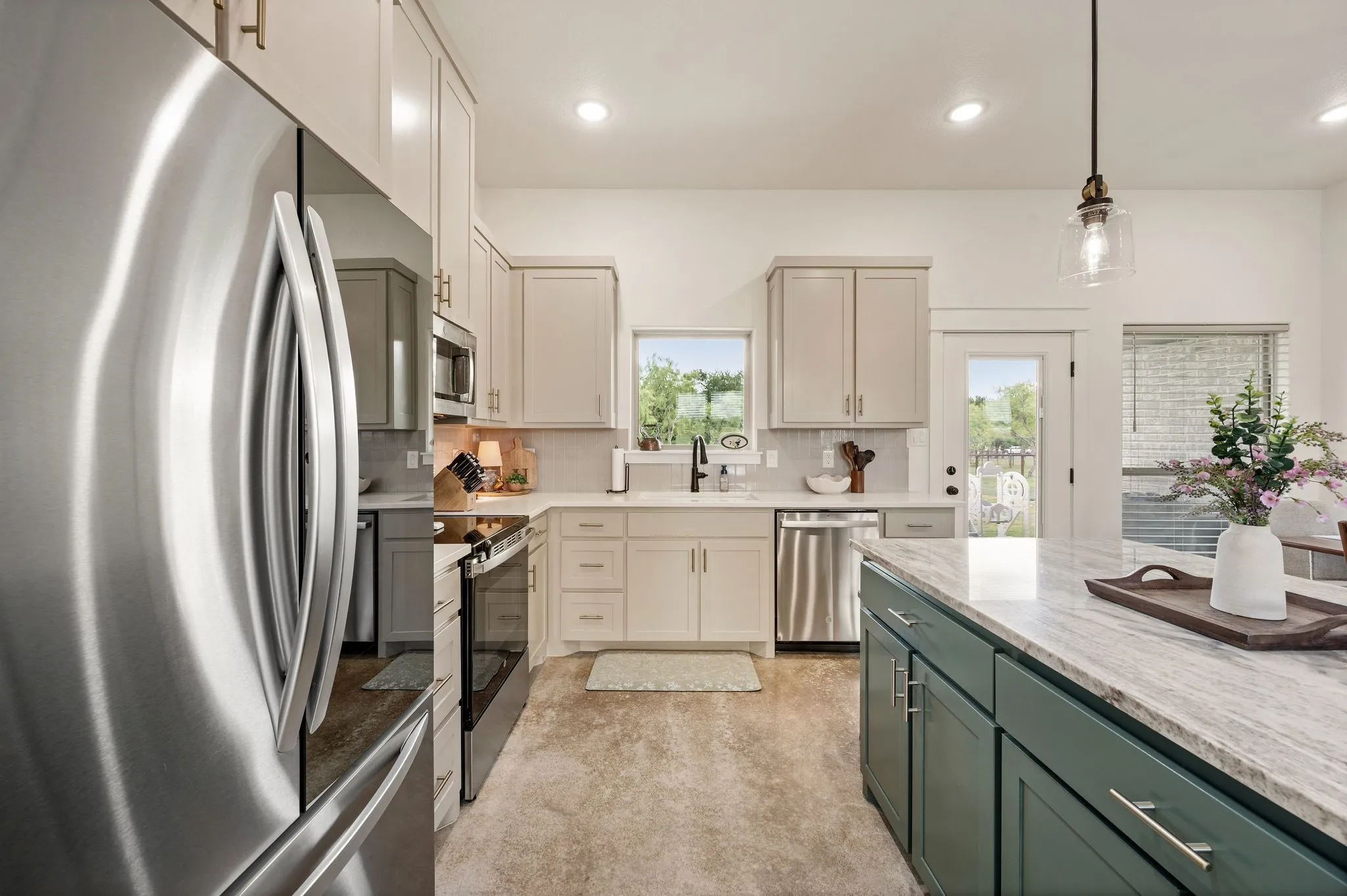 Modern kitchen featuring stainless steel appliances, light-toned cabinetry, a spacious island with a light-colored countertop, and recessed lighting