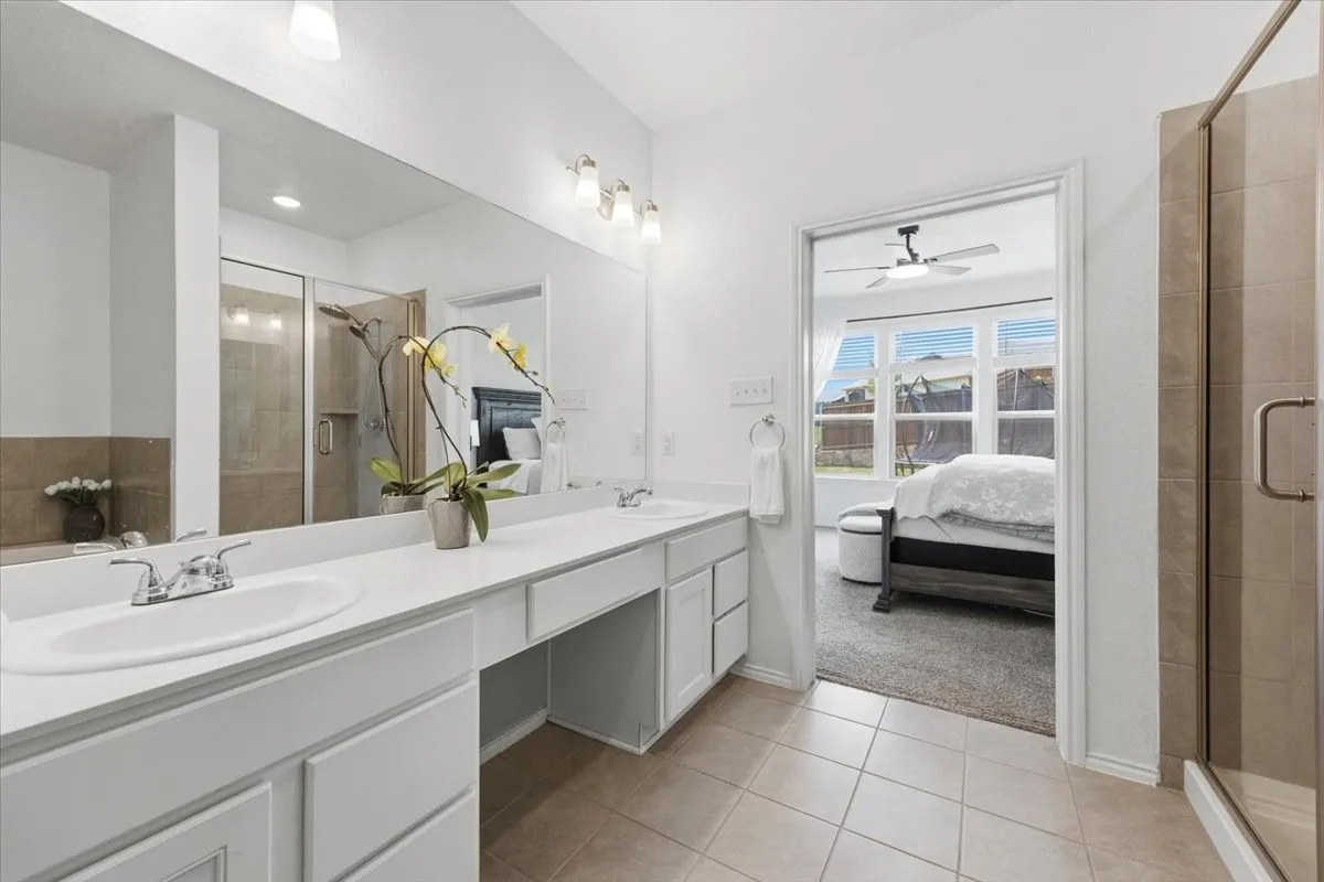 Streamlined primary bath featuring dual sinks and a separate shower.