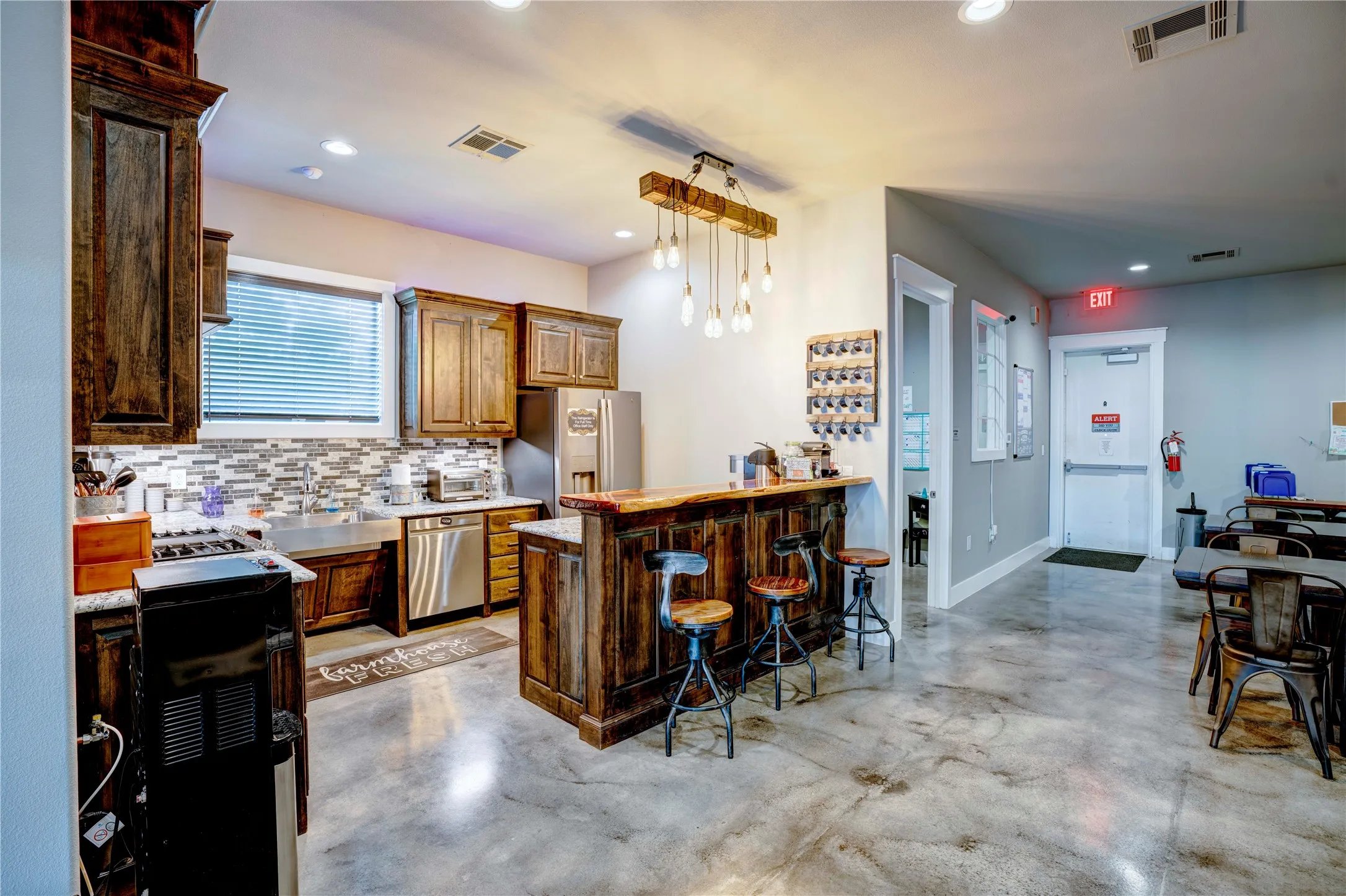 Spacious kitchen featuring dark wood cabinetry, stainless steel appliances, and a mosaic tile backsplash