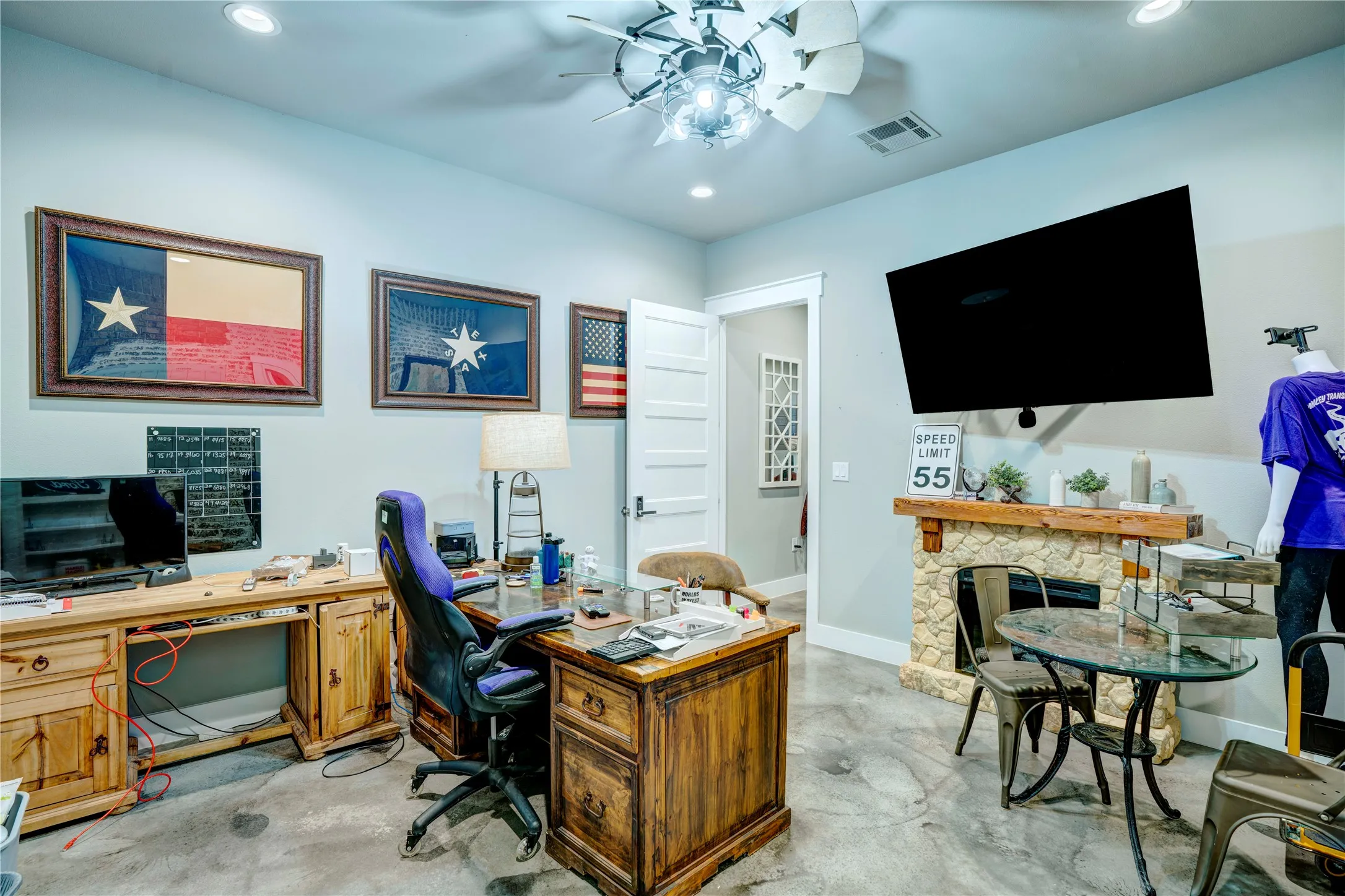 Room featuring polished concrete flooring, a stone-faced fireplace with a wood mantel, recessed lighting, and a ceiling fan