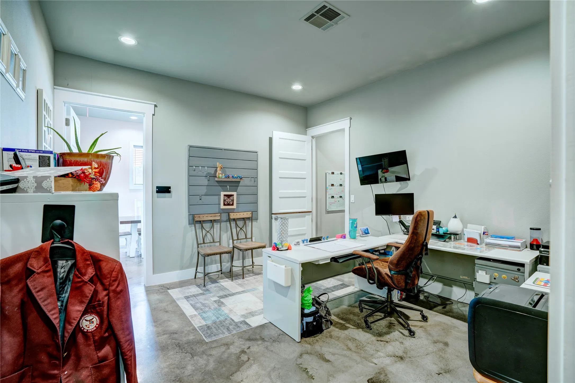 Spacious interior room featuring concrete flooring, recessed lighting, and a light gray wall color