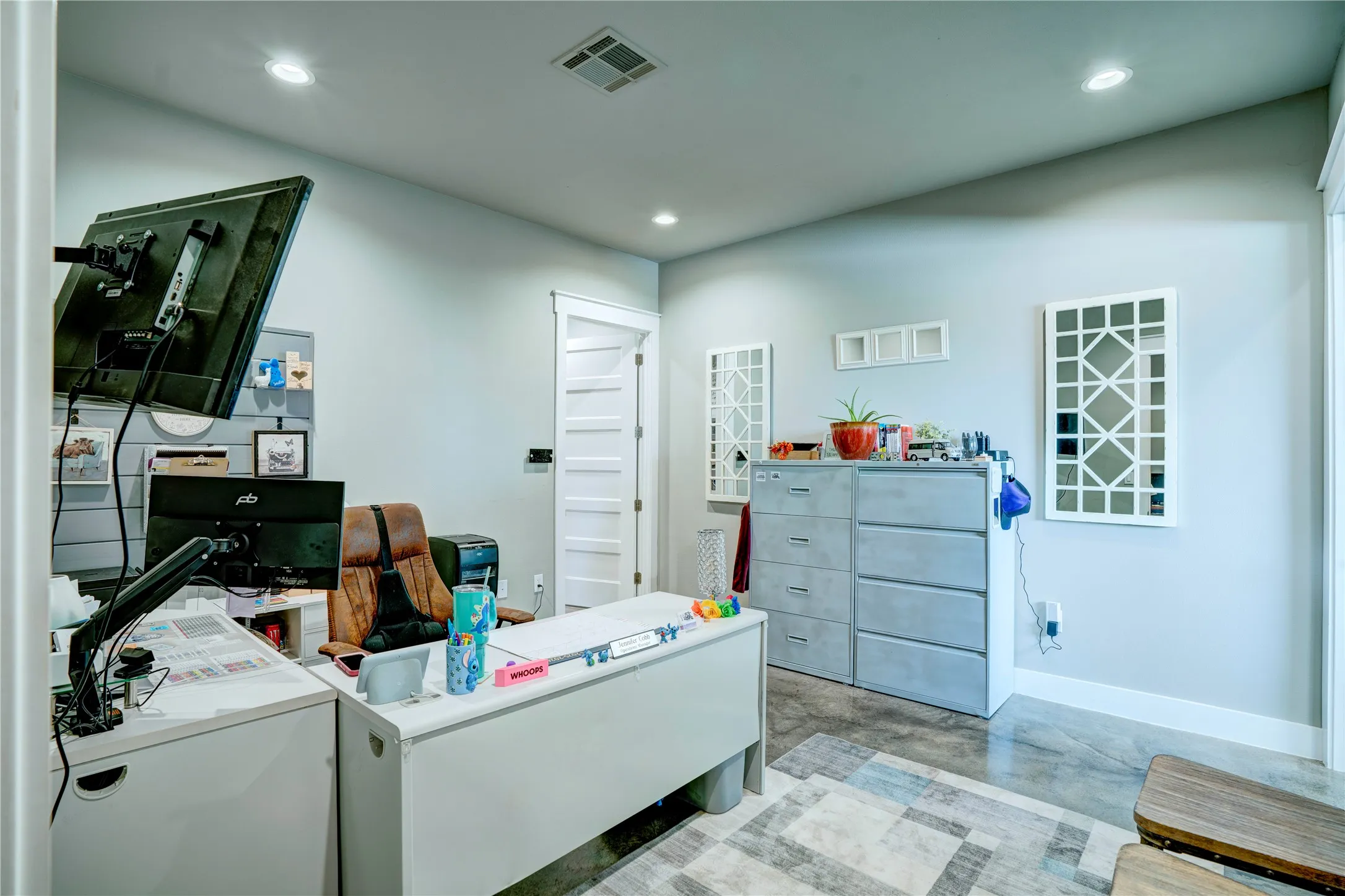 Recessed ceiling lighting illuminates this versatile room with light gray walls, dark wood-finish flooring, and white trim