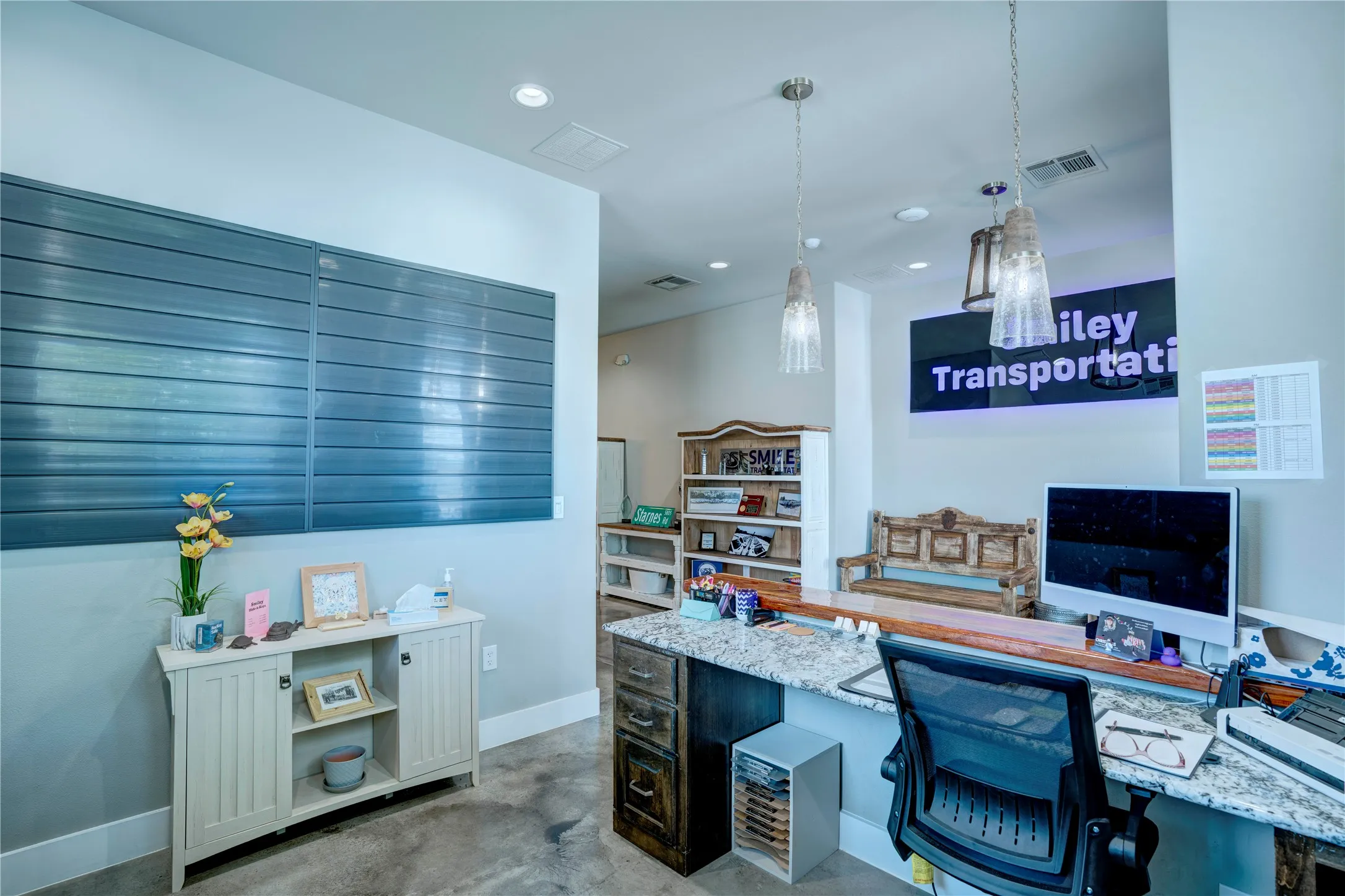 Reception area (reverse view) featuring a granite-look countertop, integrated shelving, recessed lighting, and pendant light fixtures