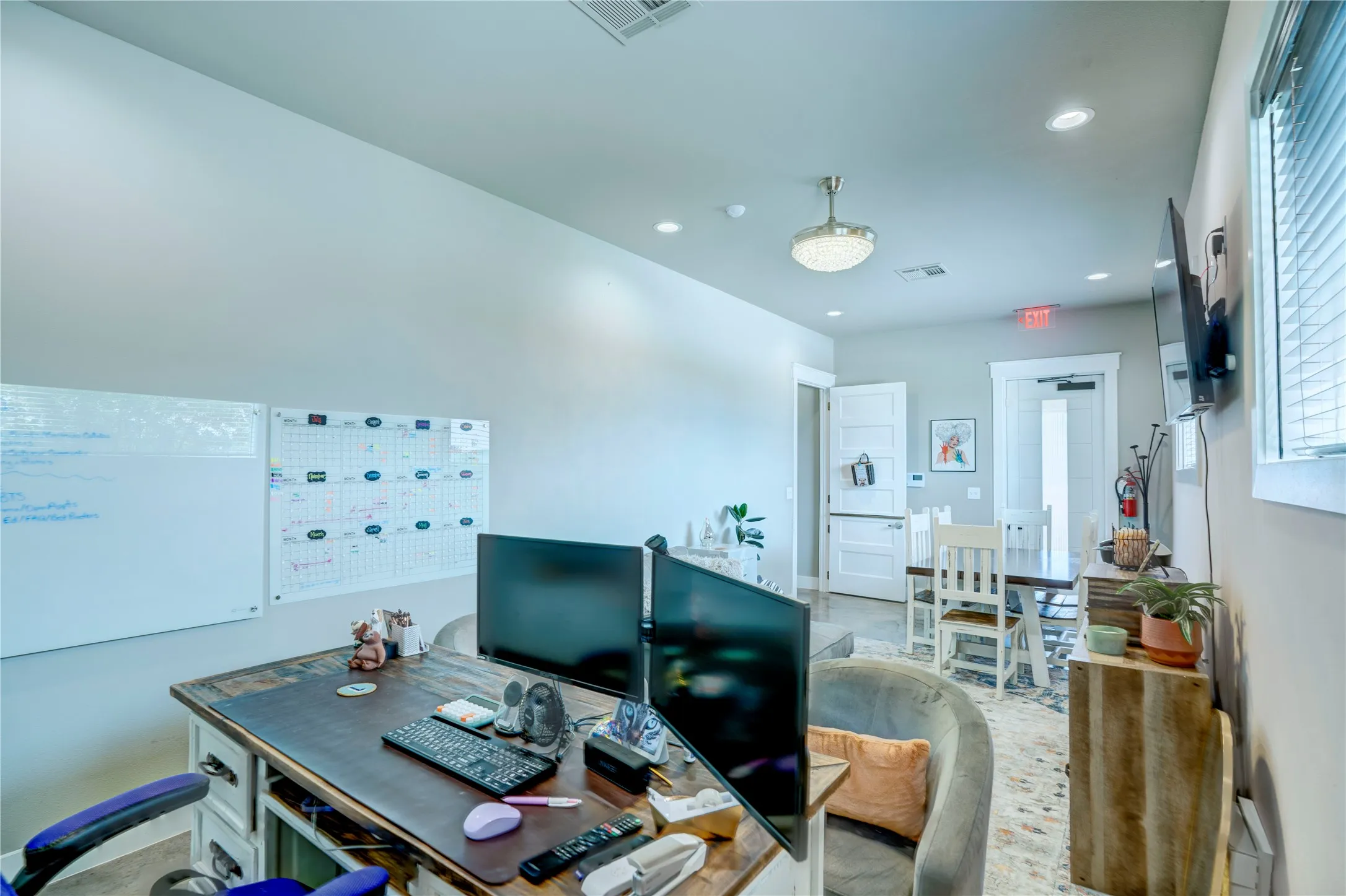 Versatile interior space featuring light gray walls, recessed lighting, a modern ceiling light fixture, and a durable desk surface