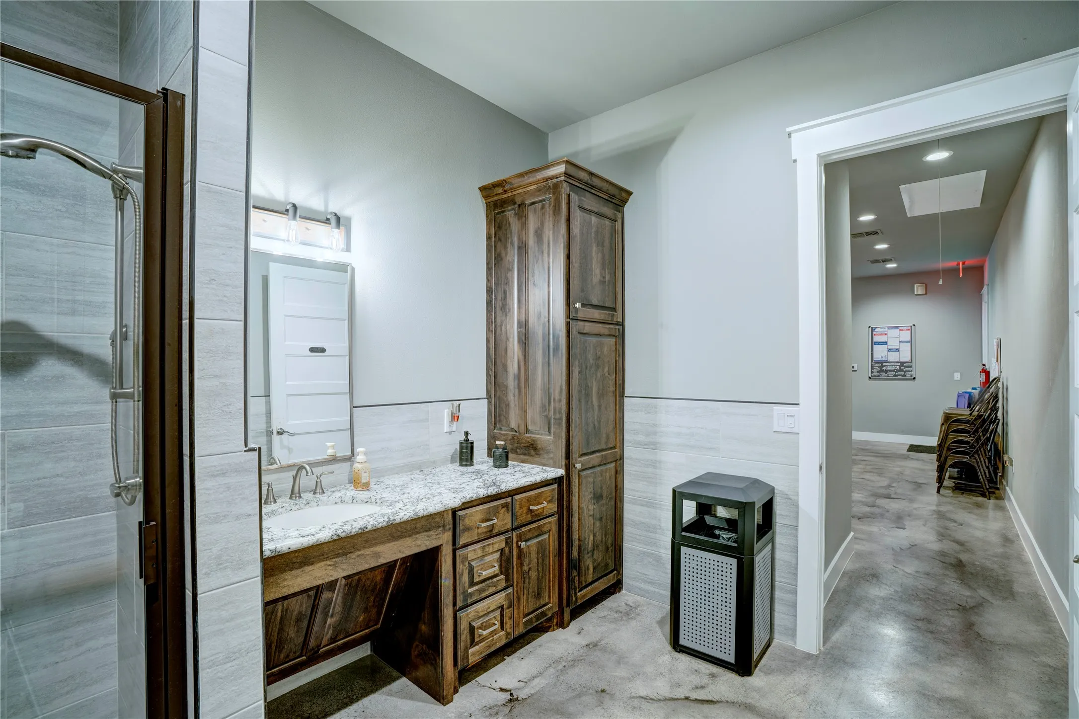 Bathroom featuring a wood-finish vanity with an undermount sink, a stone-finish countertop, and a tall wood-finish storage cabinet