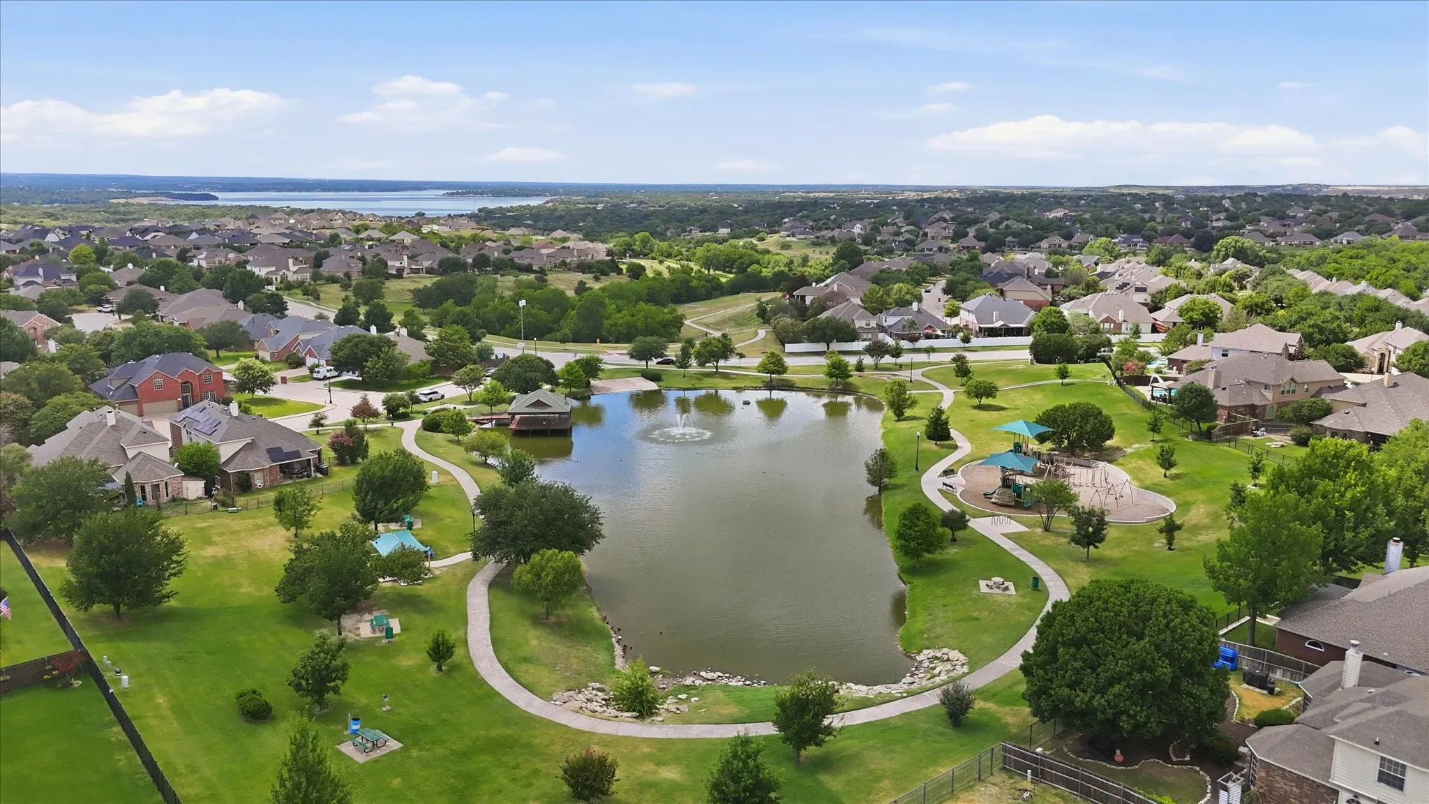 Aerial overview of a residential neighborhood featuring a central pond with a fountain