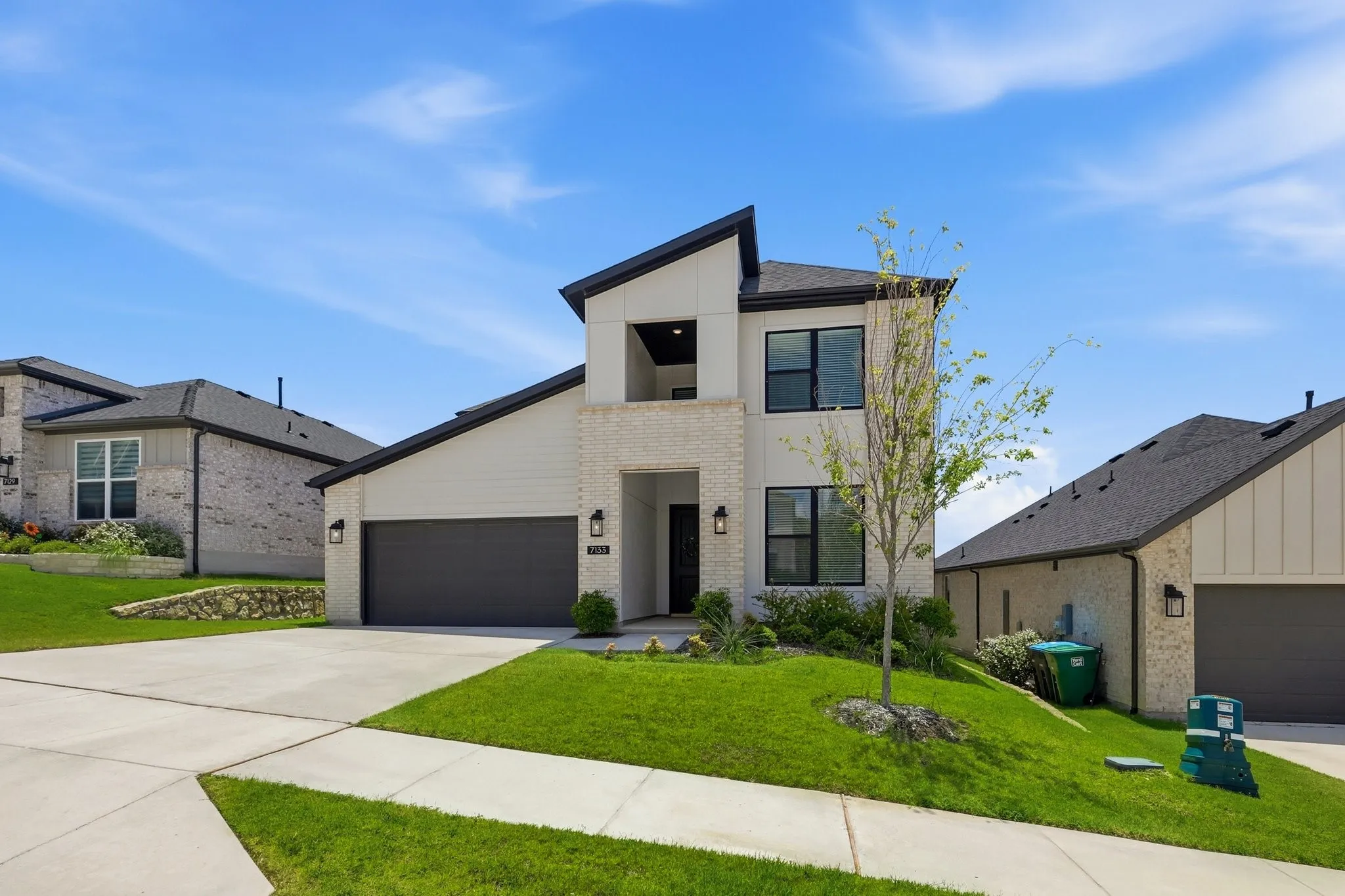Modern style two-story home featuring a black-trimmed roofline with a mix of light bright and siding.