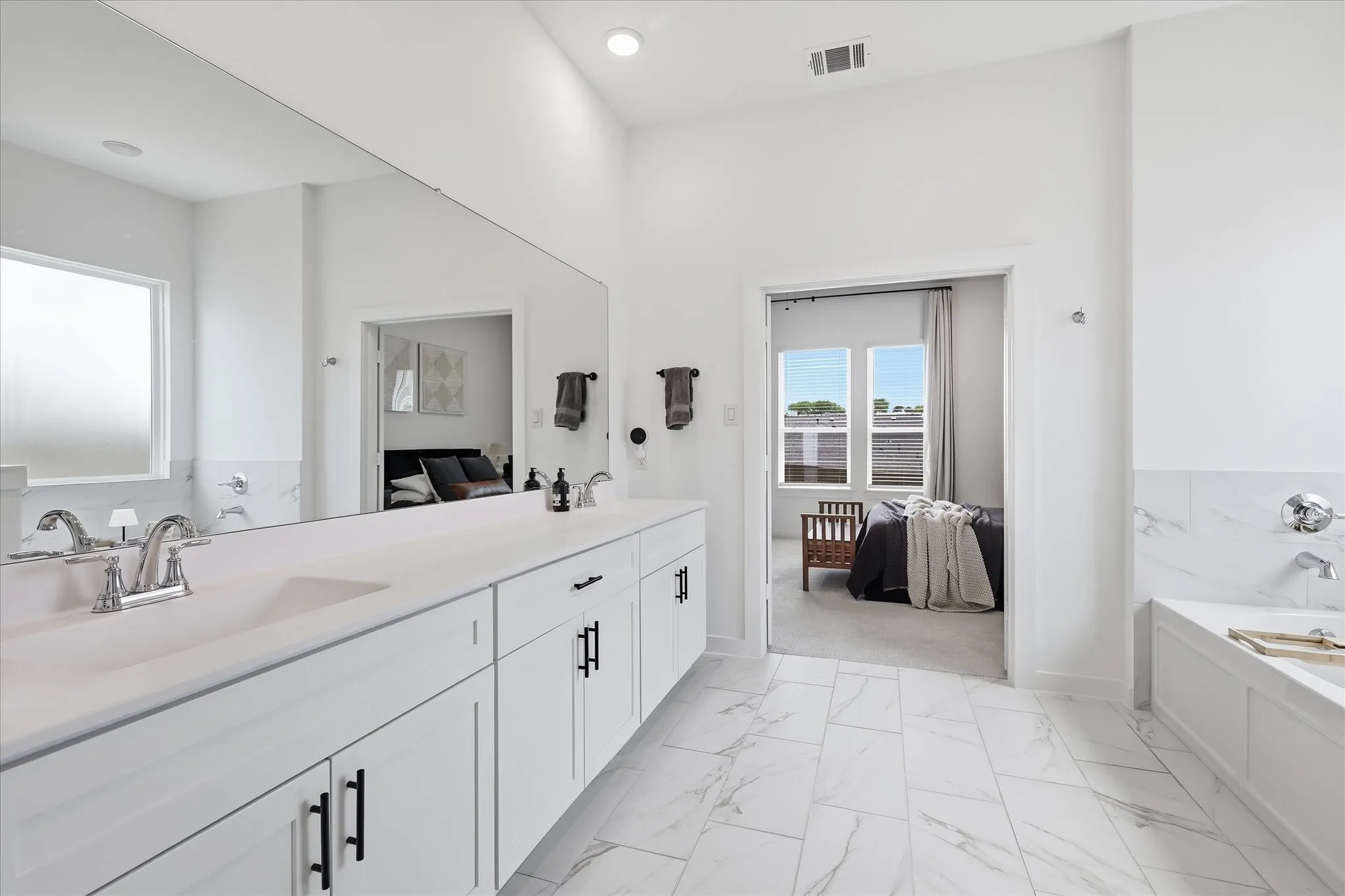 Bathroom featuring a double vanity with white cabinetry, matte black hardware, and an expansive wall-mounted mirror