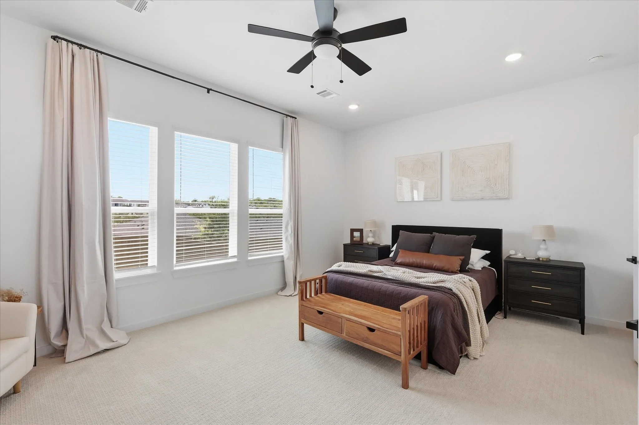 Primary bedroom with large windows that allow natural light to pour in to the room.