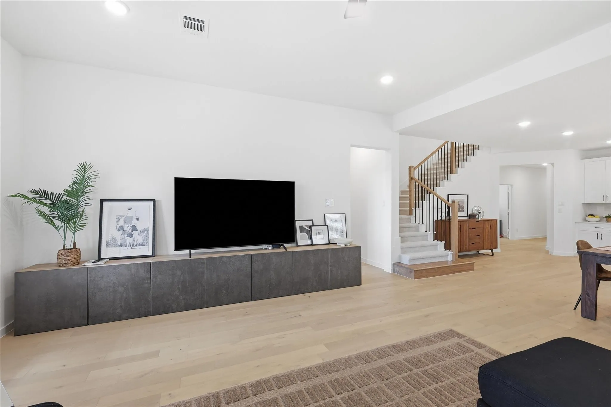 Spacious living area featuring light wood flooring and recessed lighting. Wonderful open-concept living floorplan.