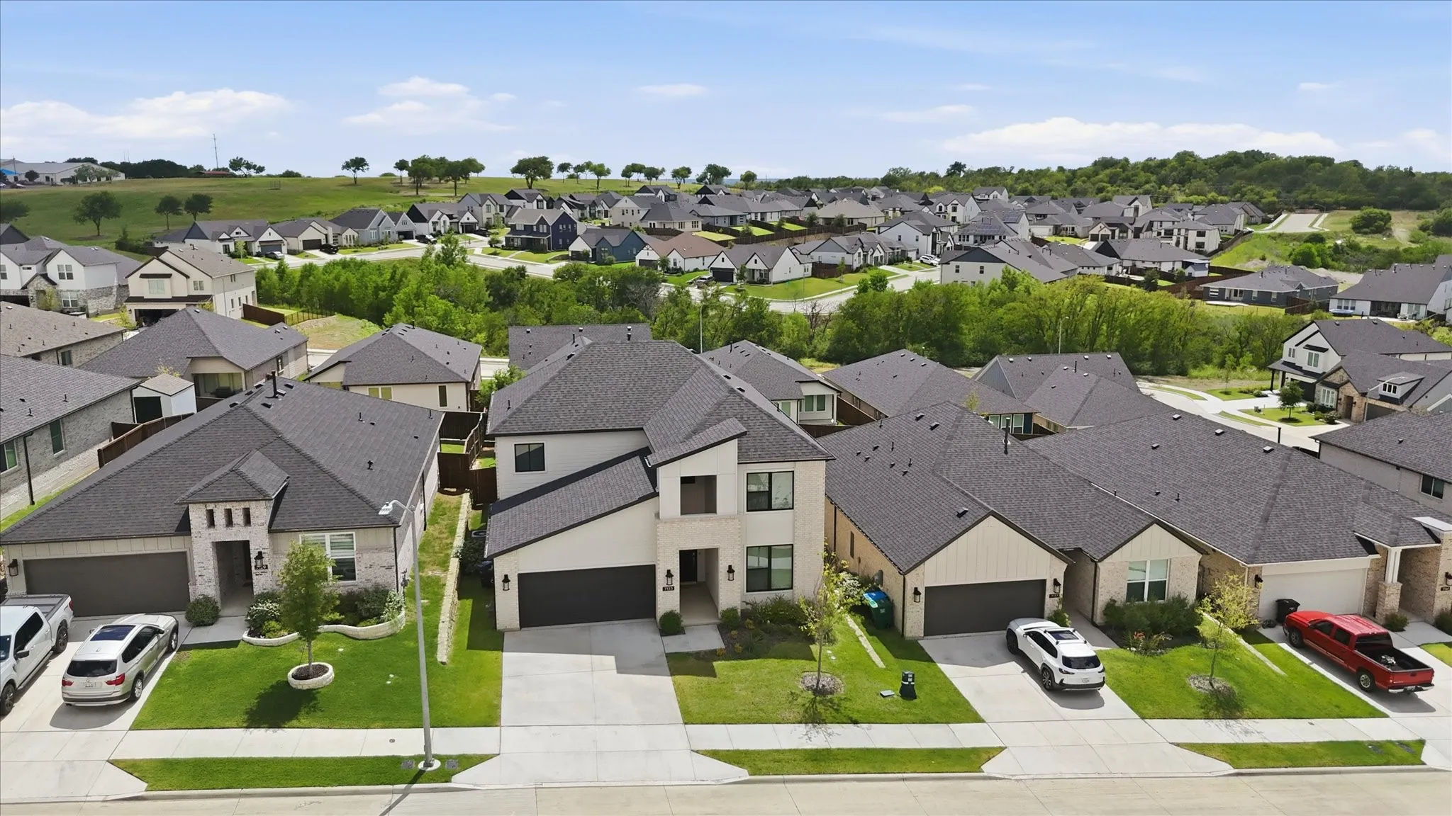 Contemporary two-story residence with a light-colored facade, dark shingle roofing, and an attached two-car garage