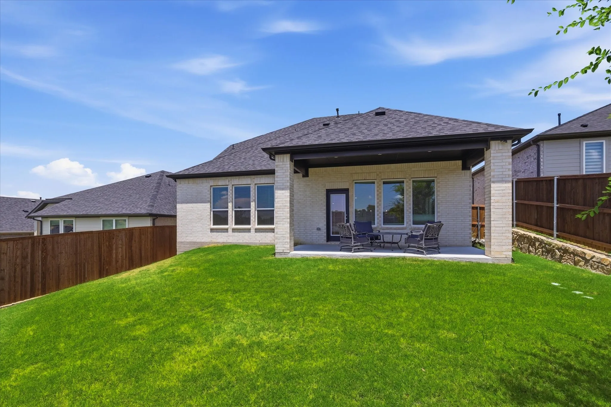 Expansive green lawn with a covered extended patio.