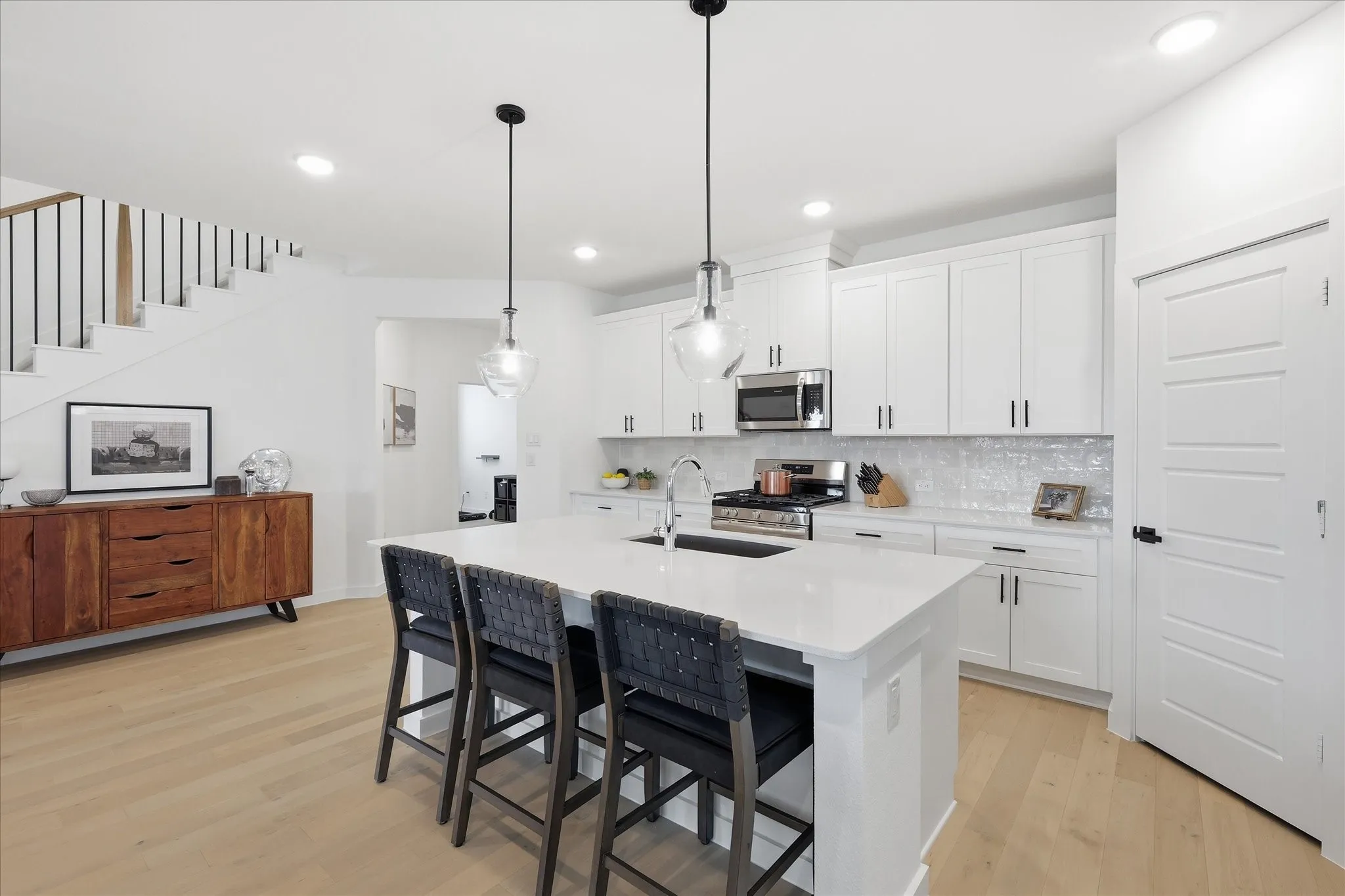Bright kitchen featuring a central island with countertop seating, stainless steel appliances, white cabinetry, and a subway tile backsplash