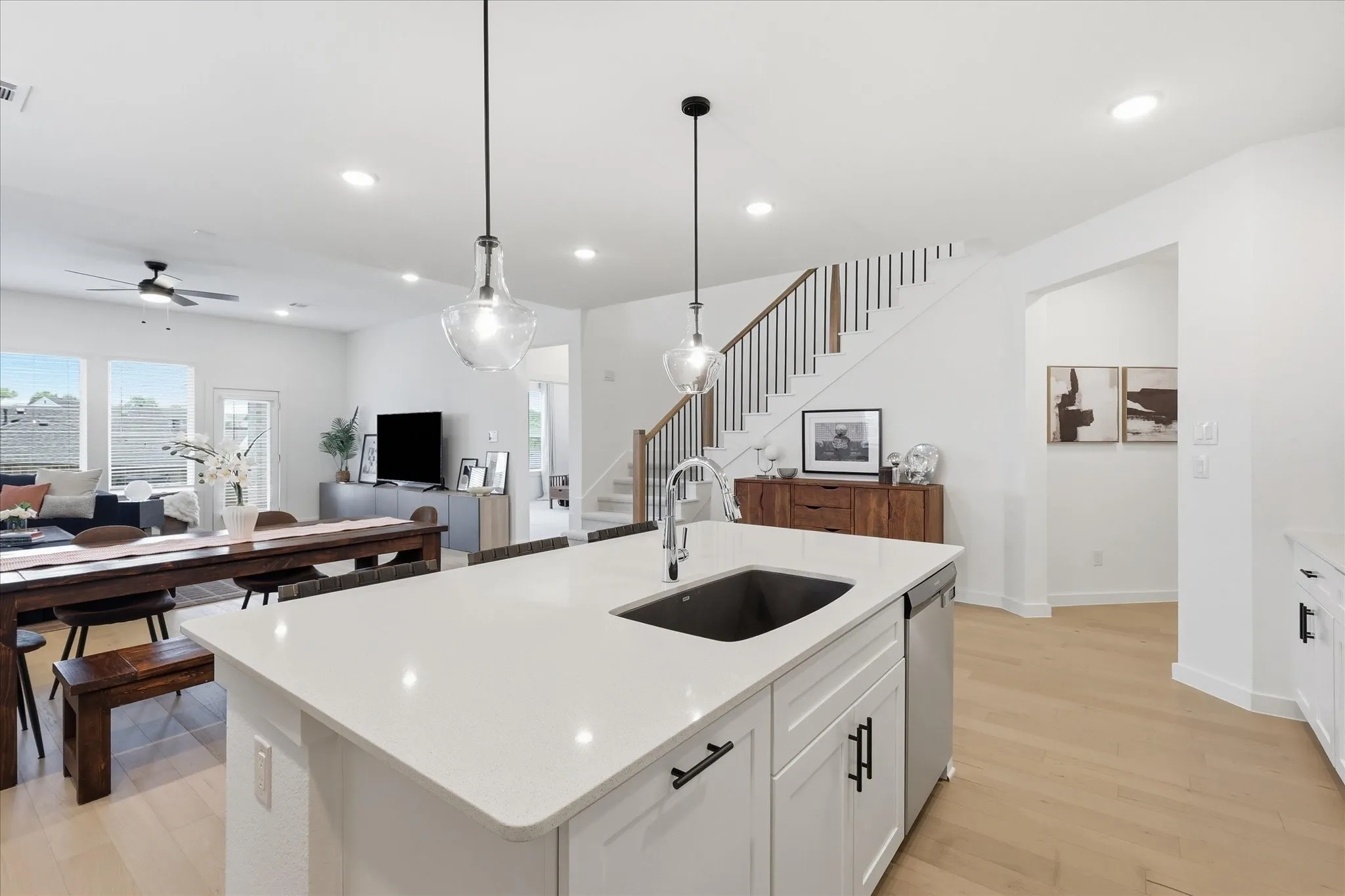Kitchen island featuring a single-basin sink, stainless steel dishwasher, and white cabinetry with matte black hardware