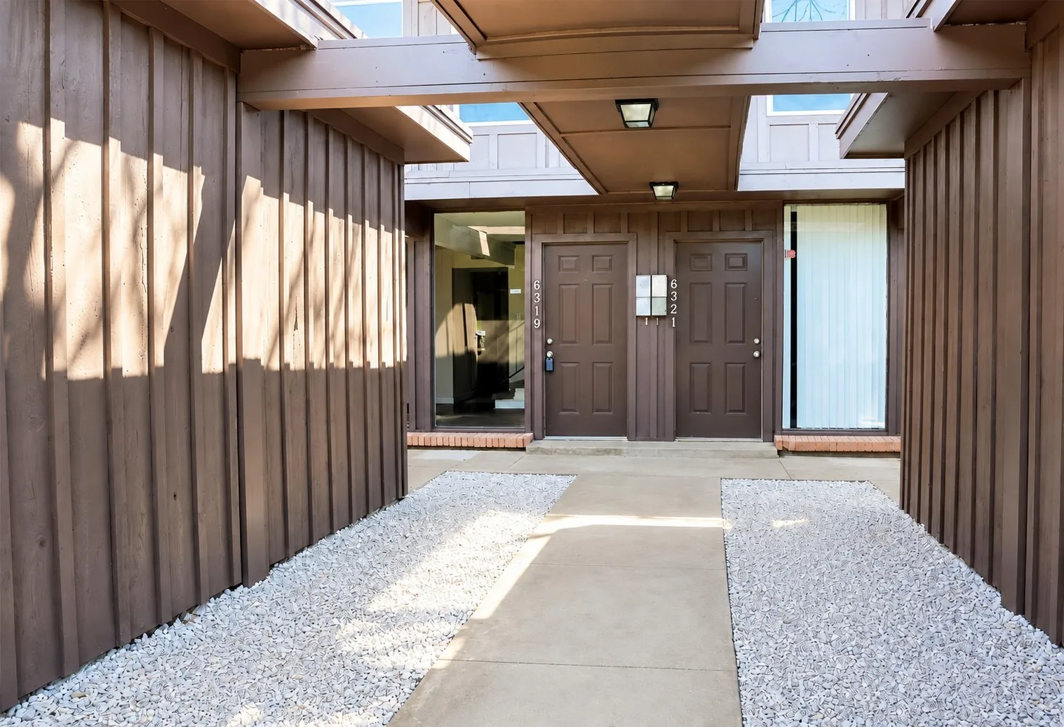 Exterior entry with concrete pathway and white gravel landscaping