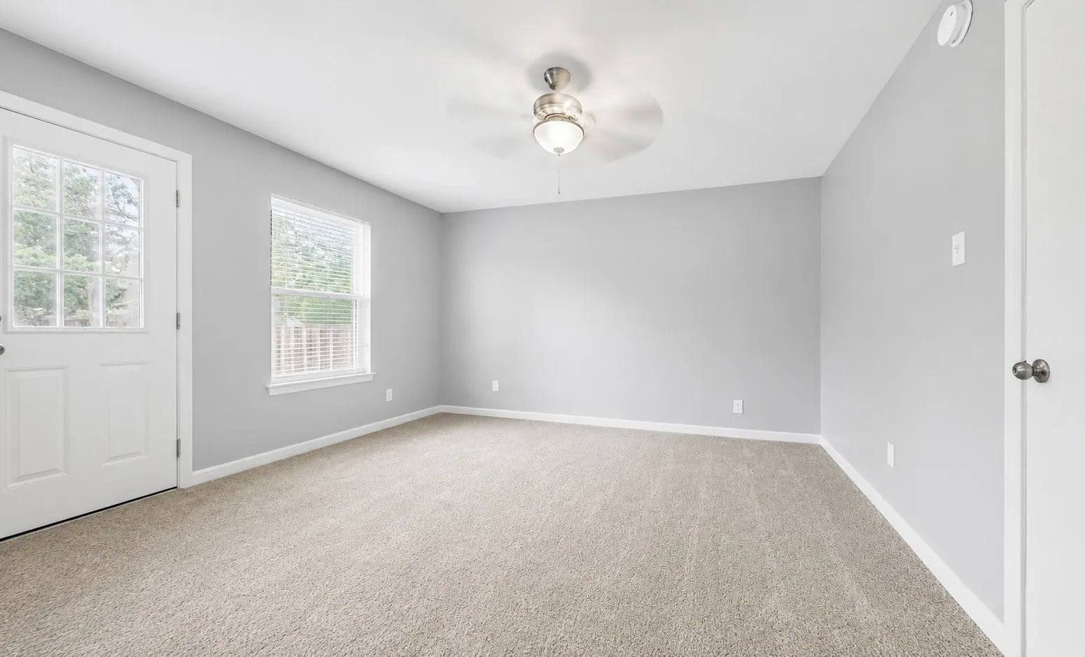 Carpeted interior space featuring light grey wall tones and white baseboards