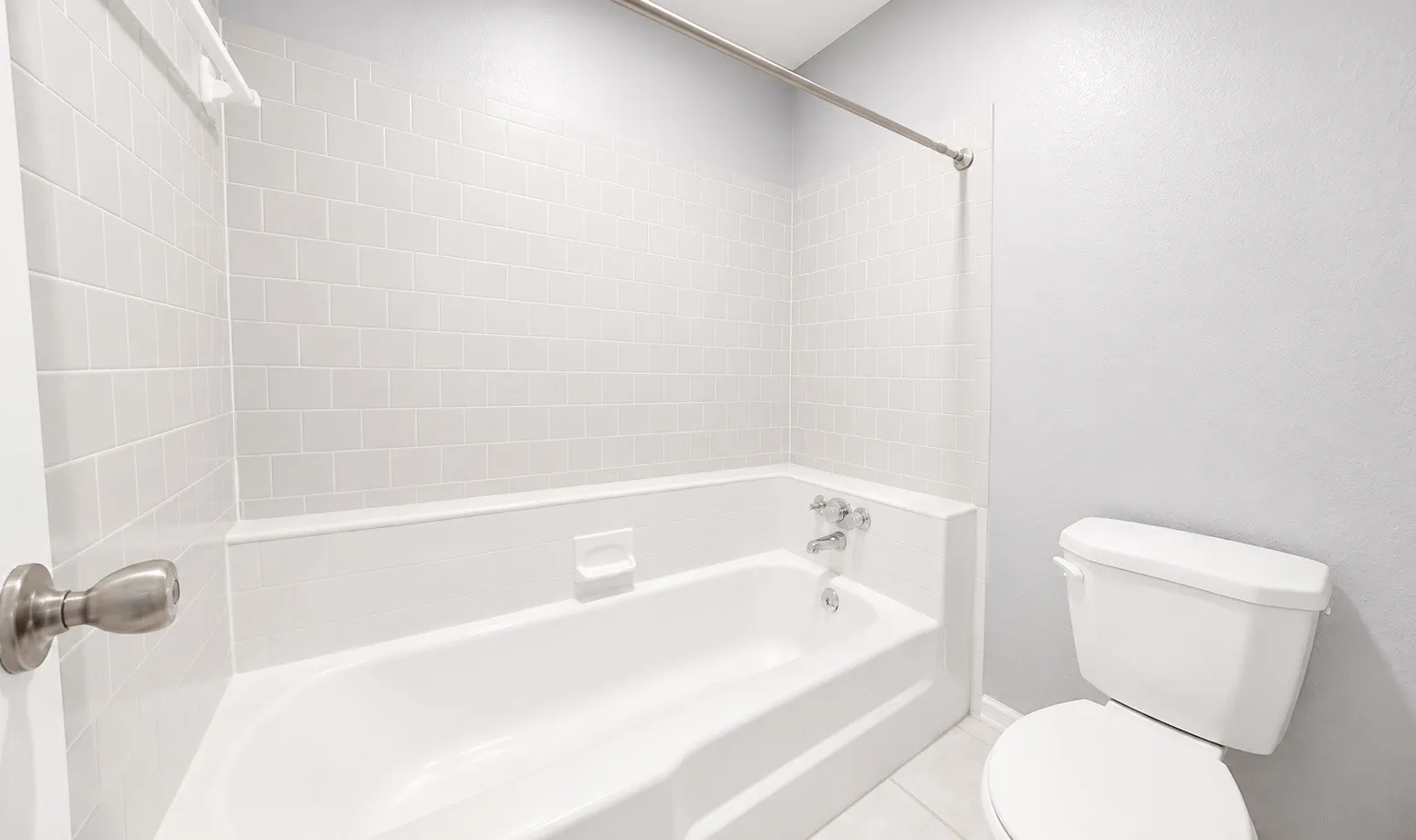 Crisp white subway tile surround, white bathtub, chrome fixtures, and a white toilet