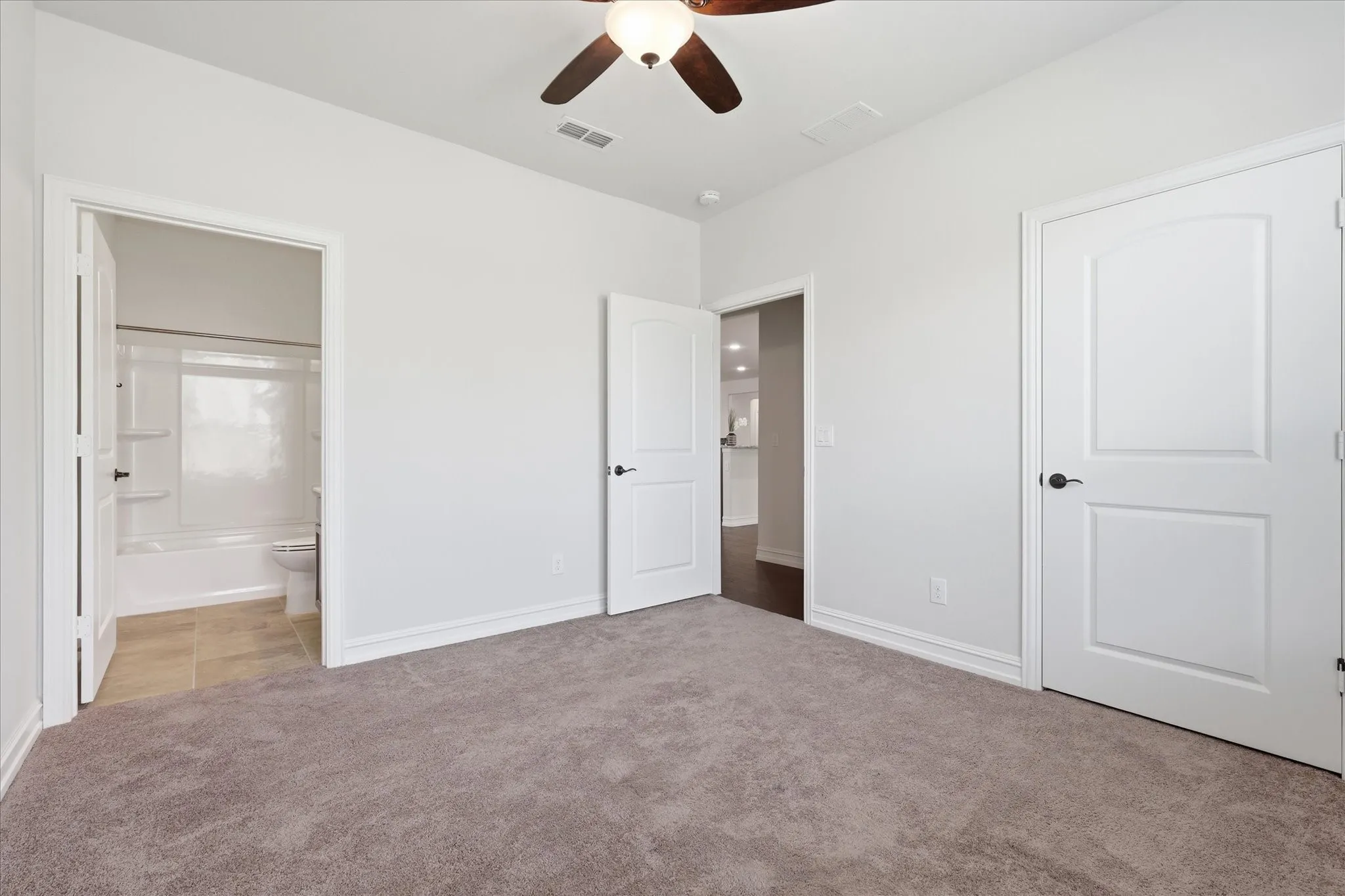 Carpeted room with white walls, featuring a ceiling fan with light fixture