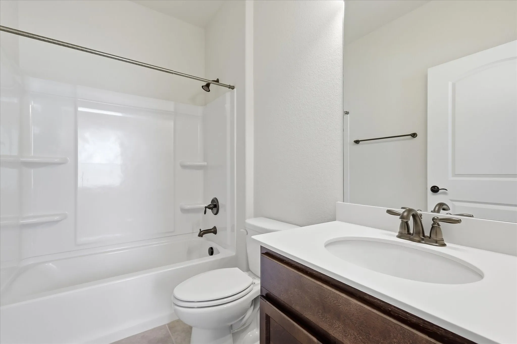 Full Guest Ensuite bathroom featuring a white tub and shower combination with oil-rubbed bronze fixtures, a white oval undermount sink, a white countertop, and wood-finish cabinetry