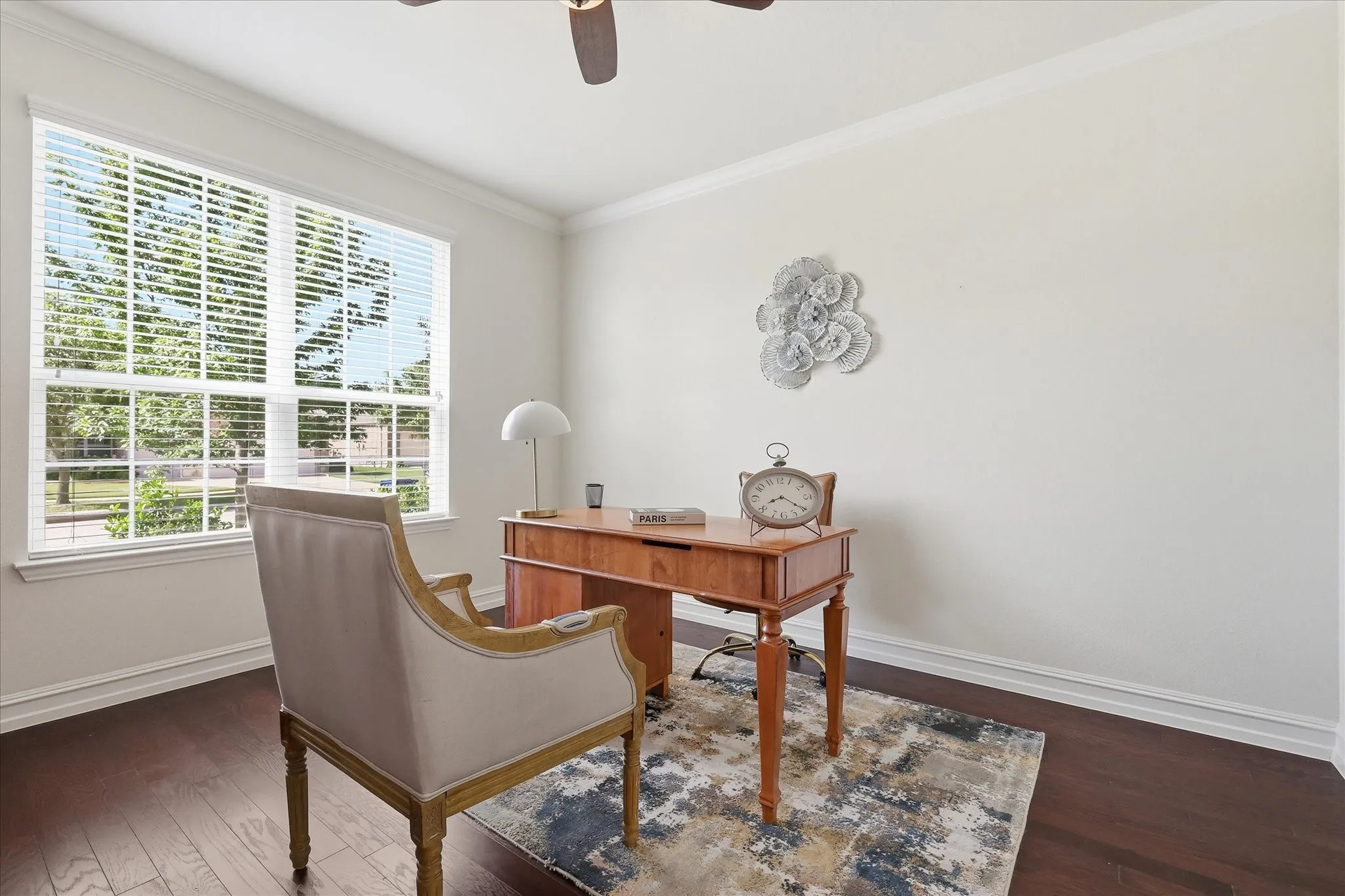 Spacious room featuring a large window with blinds, dark wood-finish flooring, white baseboards, and white crown molding