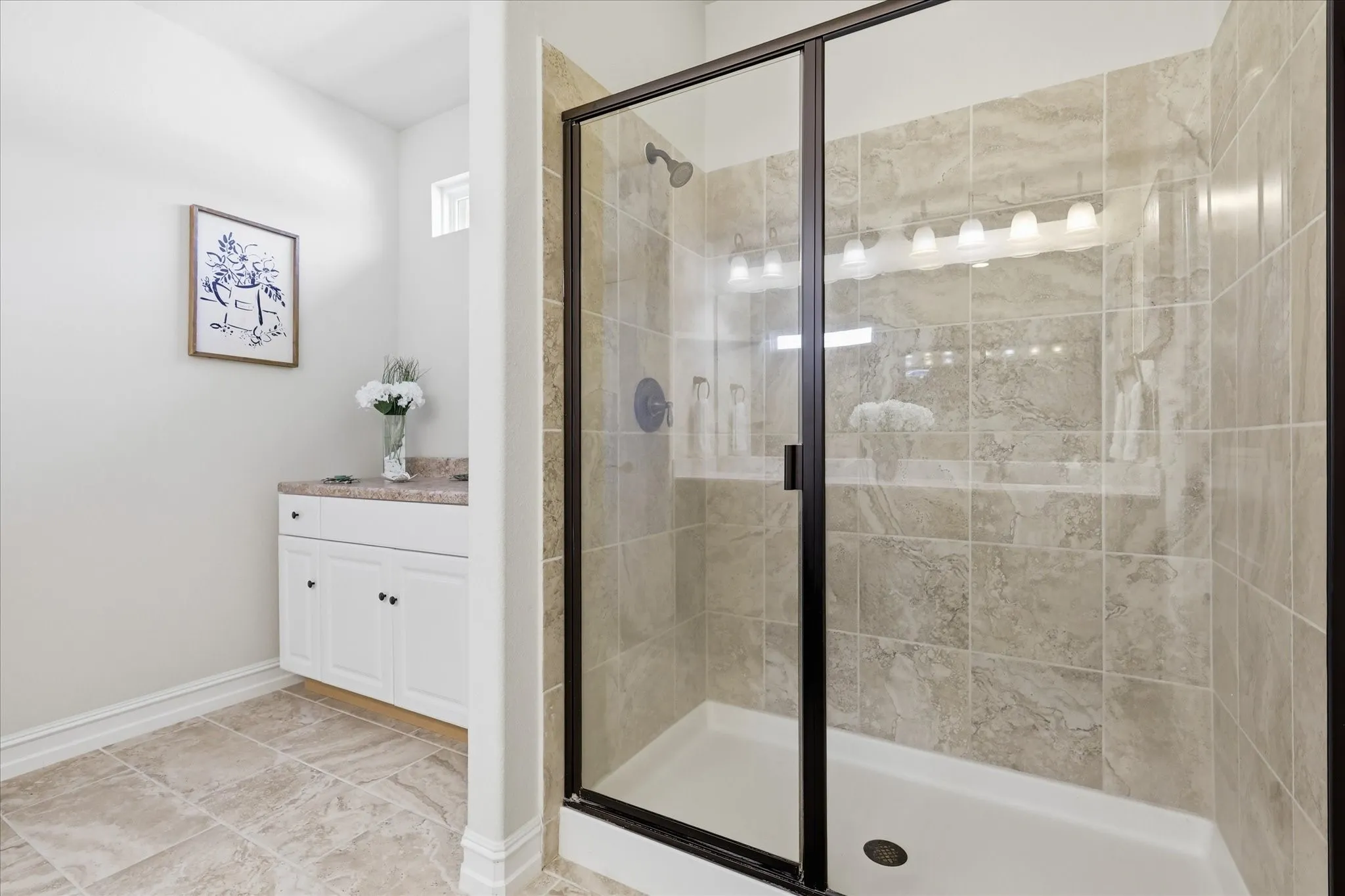Walk In Shower with a framed glass door, featuring neutral-toned tile surround and an integrated shower shelf